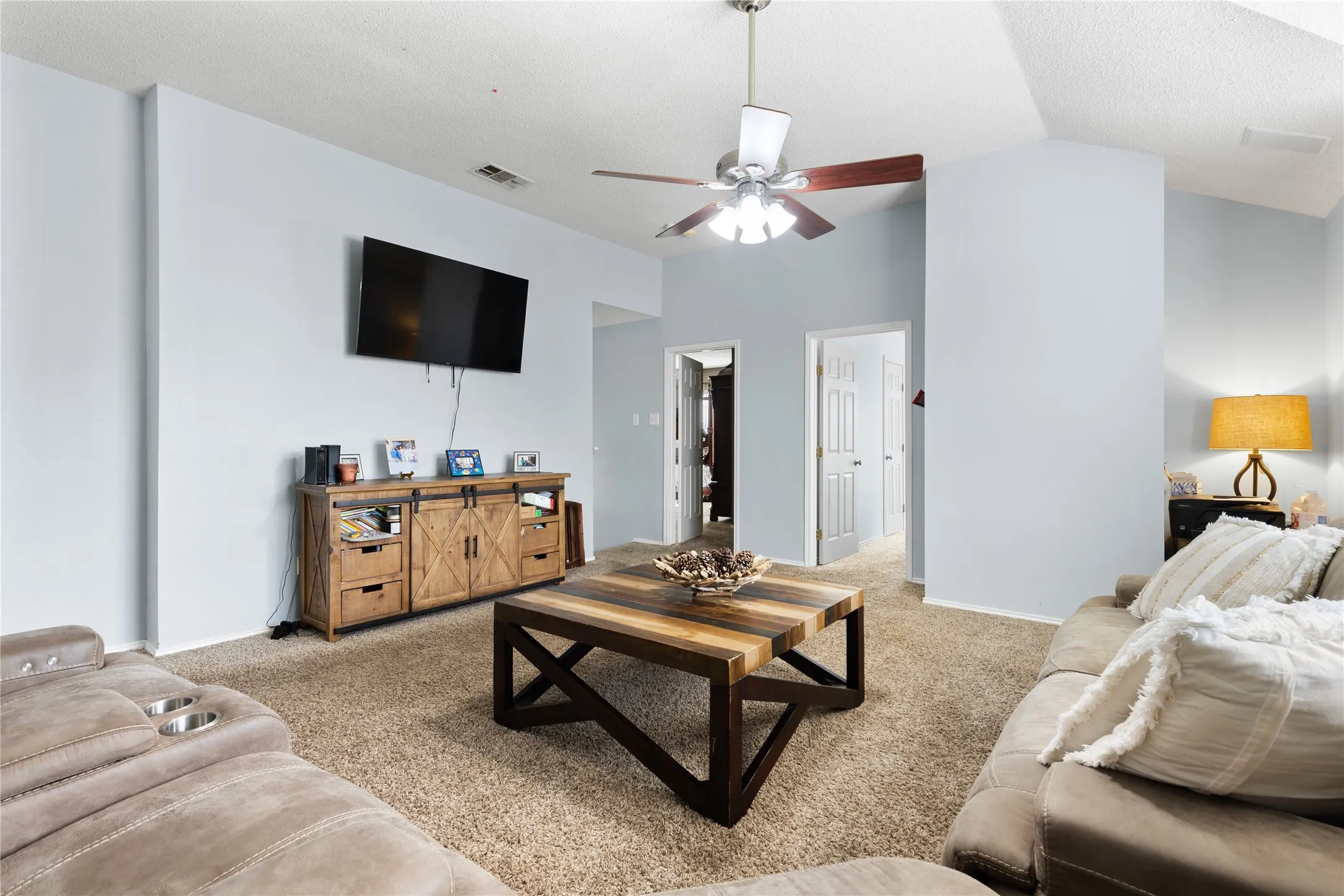 Vaulted ceilings enhance this living space featuring light blue walls and carpet flooring