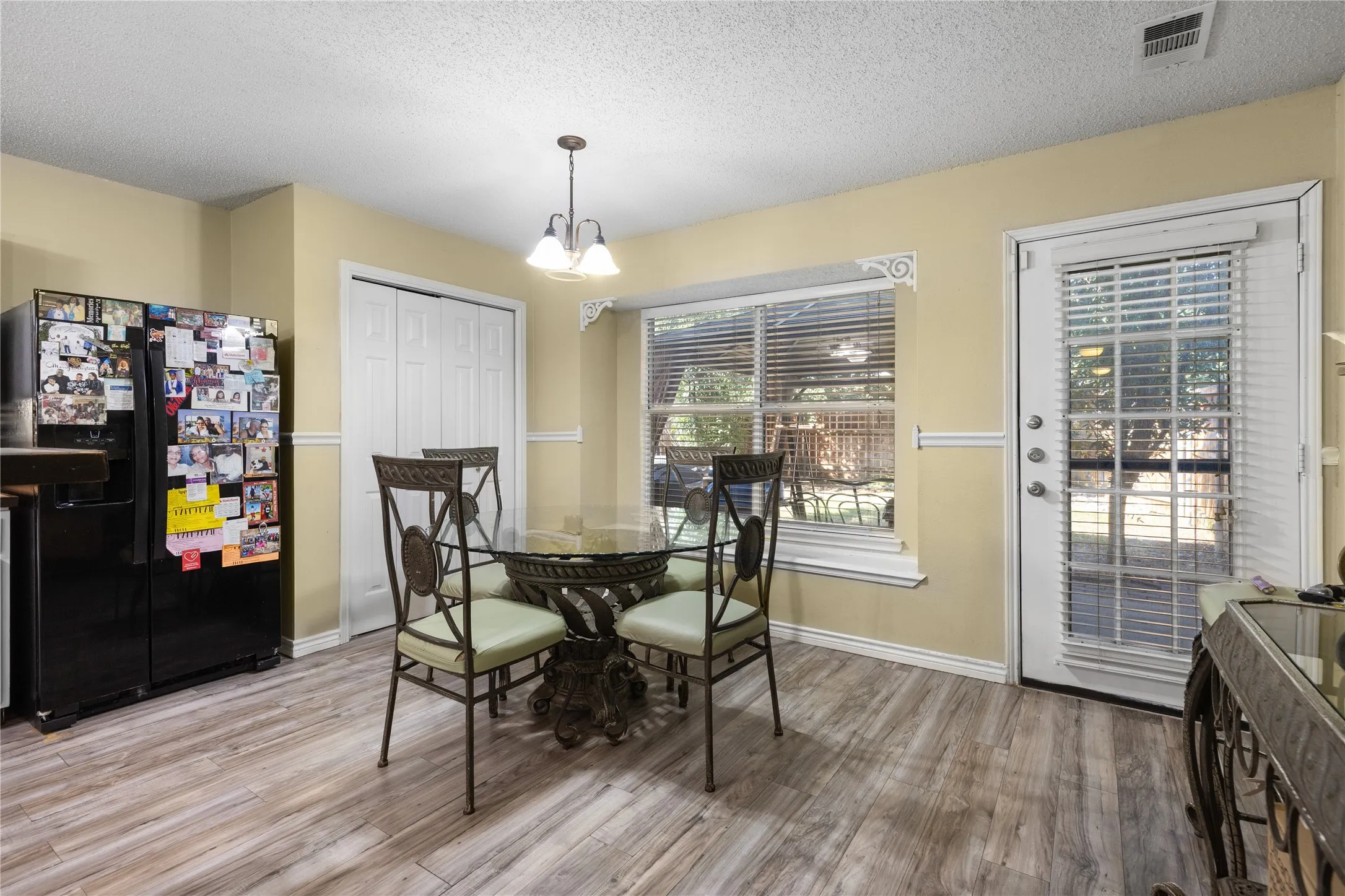 Kitchen area featuring wood-finish flooring, a window with horizontal blinds, and a glass-paneled door