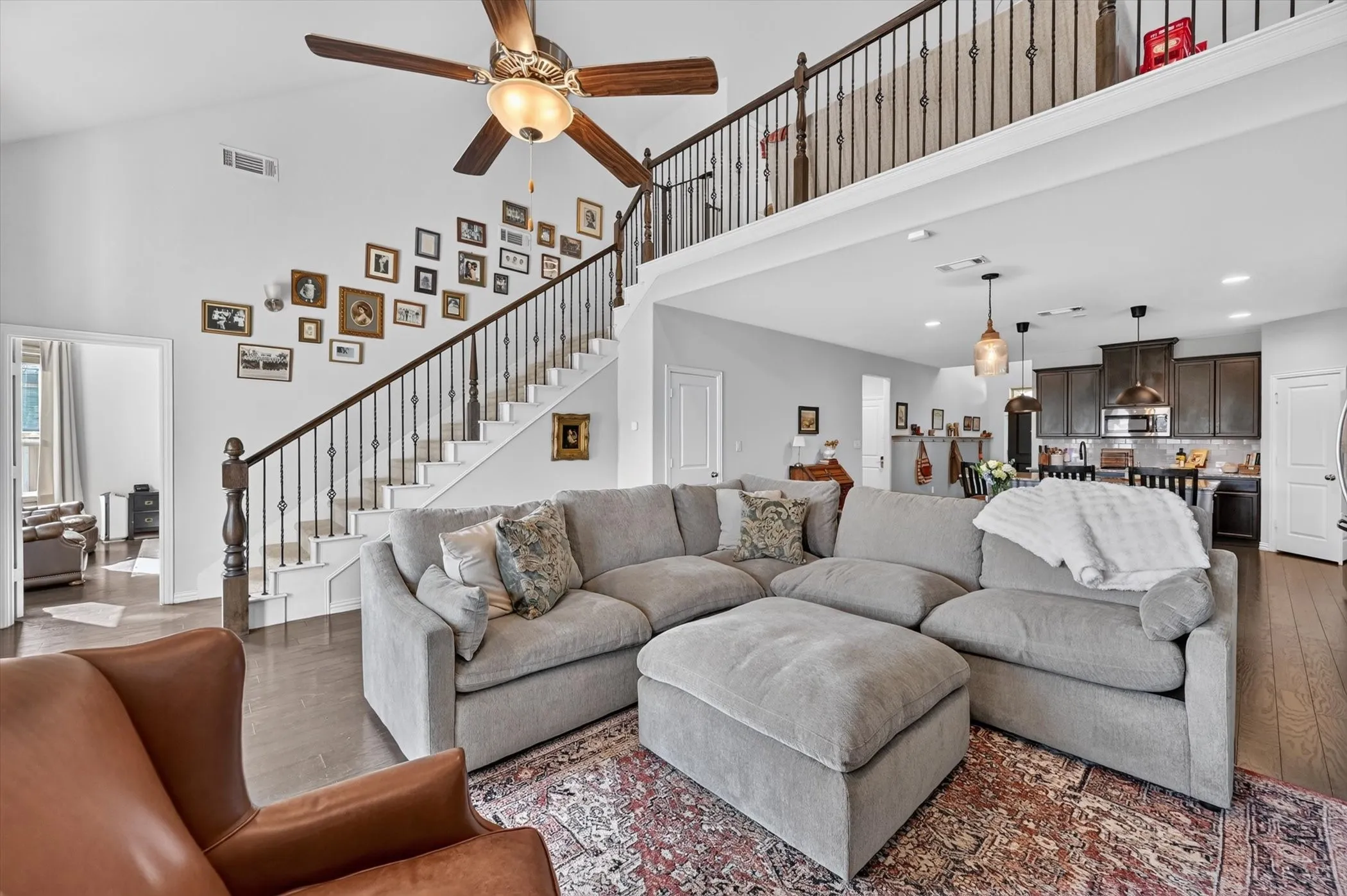 Open-concept living area with a two-story ceiling, wood-finish flooring, and a large ceiling fan