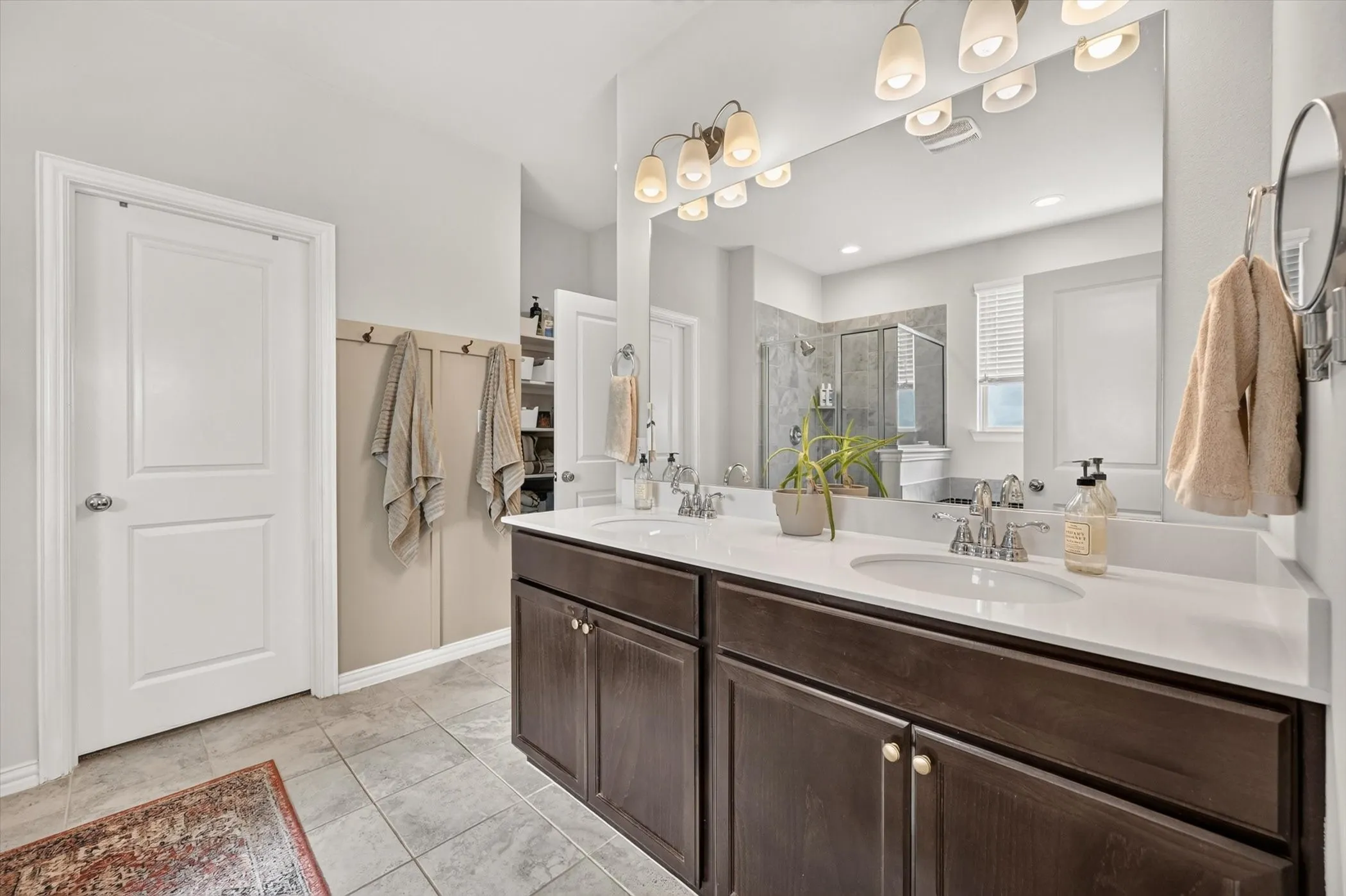 Double vanity featuring dark wood-finish cabinetry, white countertops, and chrome fixtures