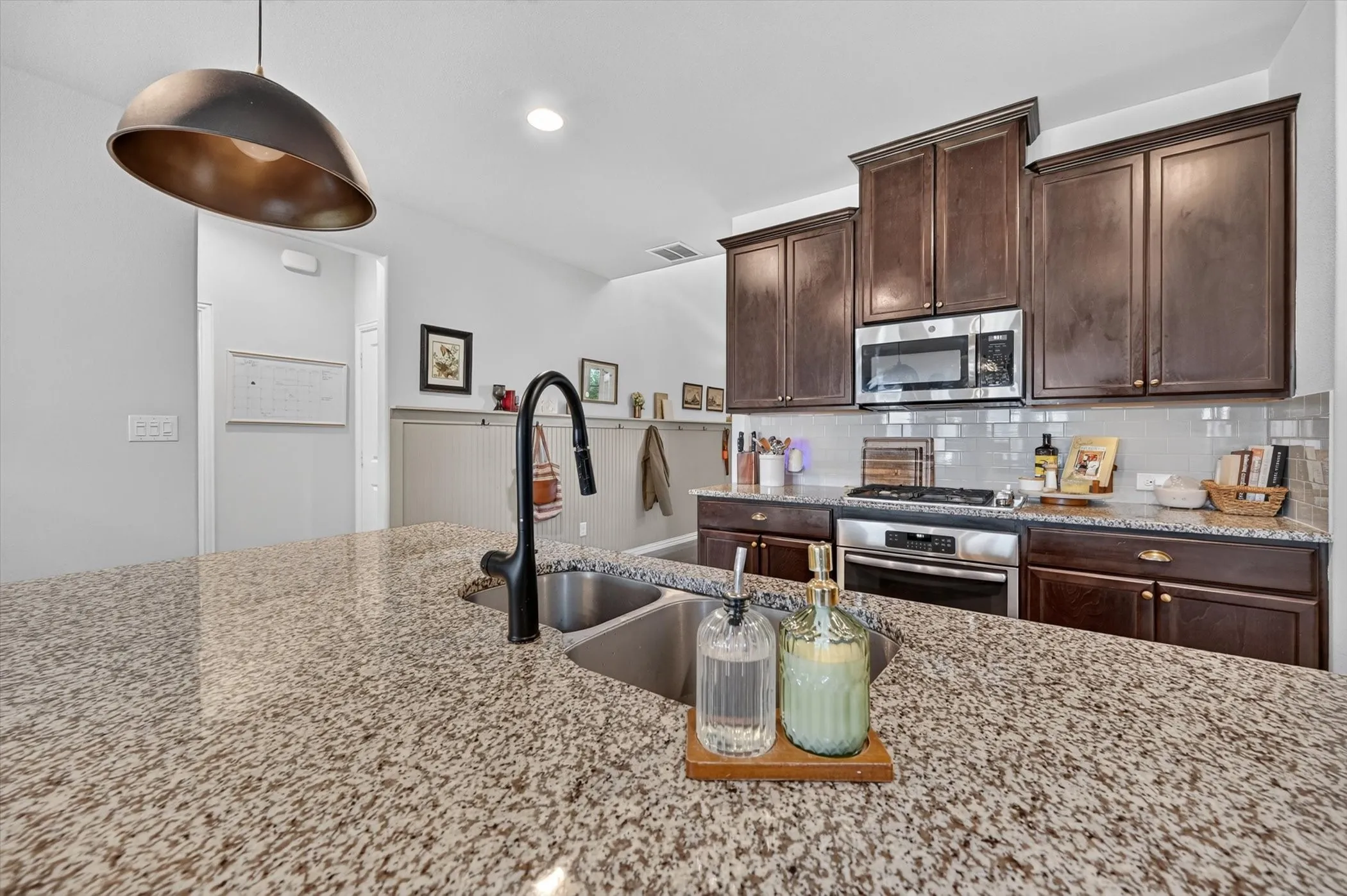 Kitchen island featuring a double basin sink and black gooseneck faucet