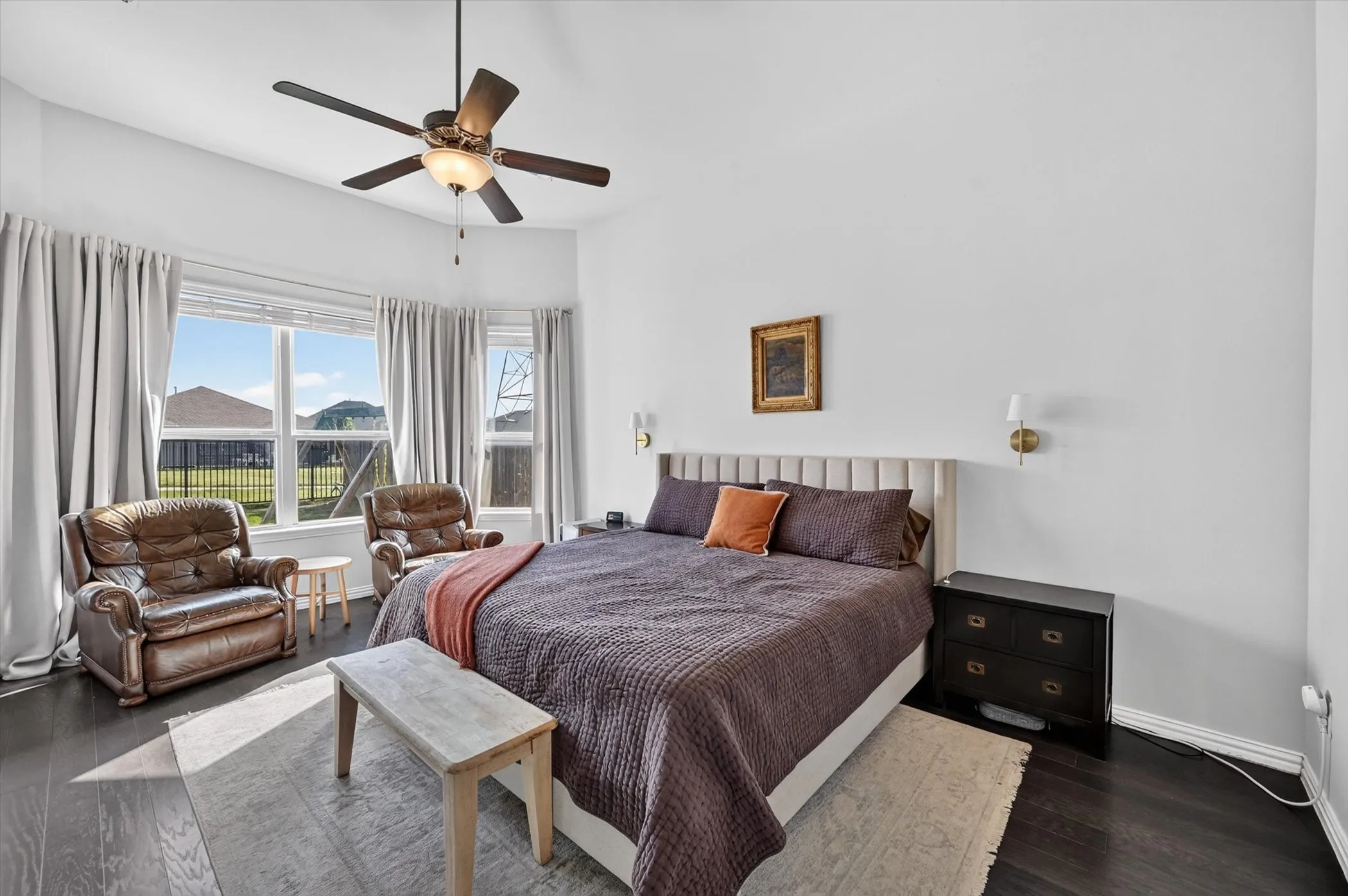 Spacious bedroom featuring dark wood-finish flooring and a multi-pane bay window
