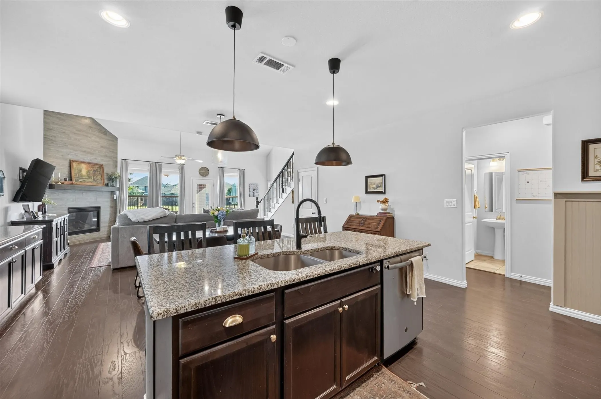 Central kitchen island with a granite countertop, double basin sink, and pendant lighting