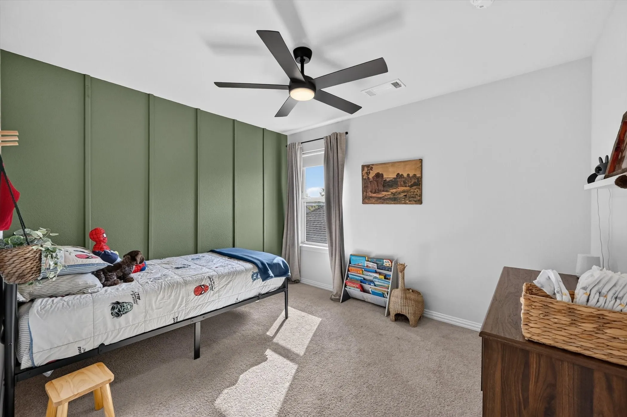 Room featuring a green accent wall with vertical paneling, light-colored carpeting, a window with drapery, and a ceiling fan with integrated lighting