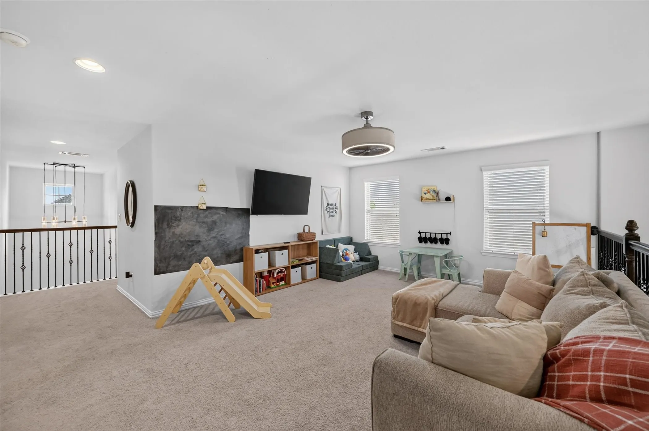 Spacious loft area featuring light gray carpeting, multiple windows with blinds, and white wall finishes