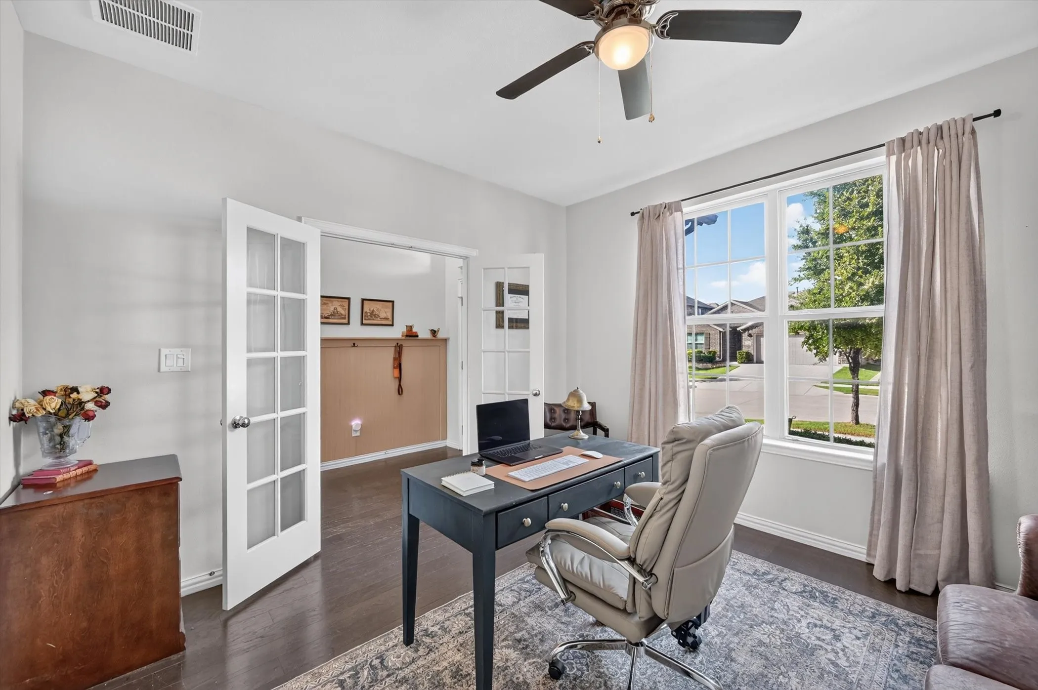Room featuring dark wood-finish flooring, white walls, and a ceiling fan with integrated lighting
