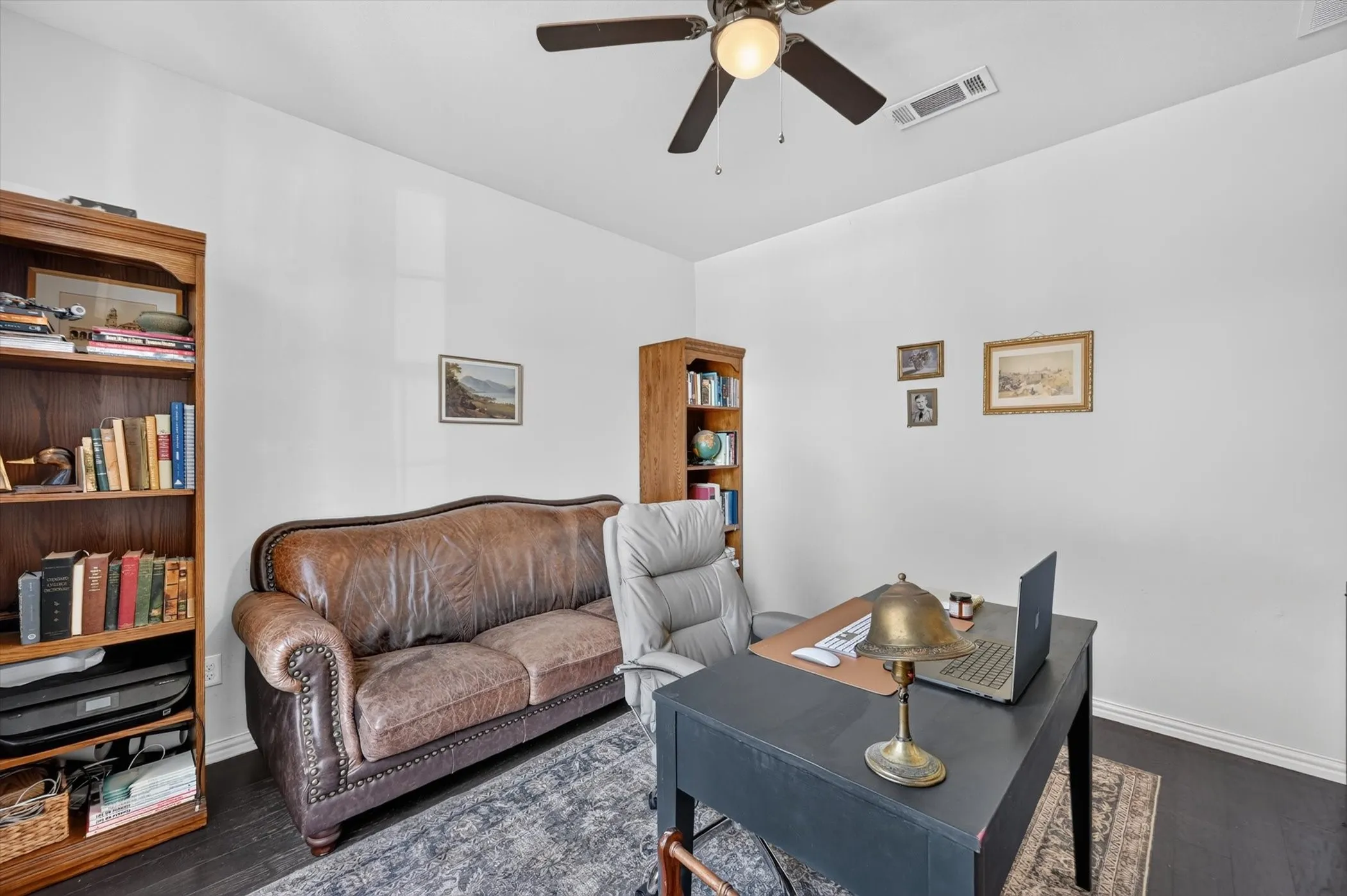 Dedicated interior space featuring dark wood-finish flooring, white walls, and a ceiling fan with integrated lighting
