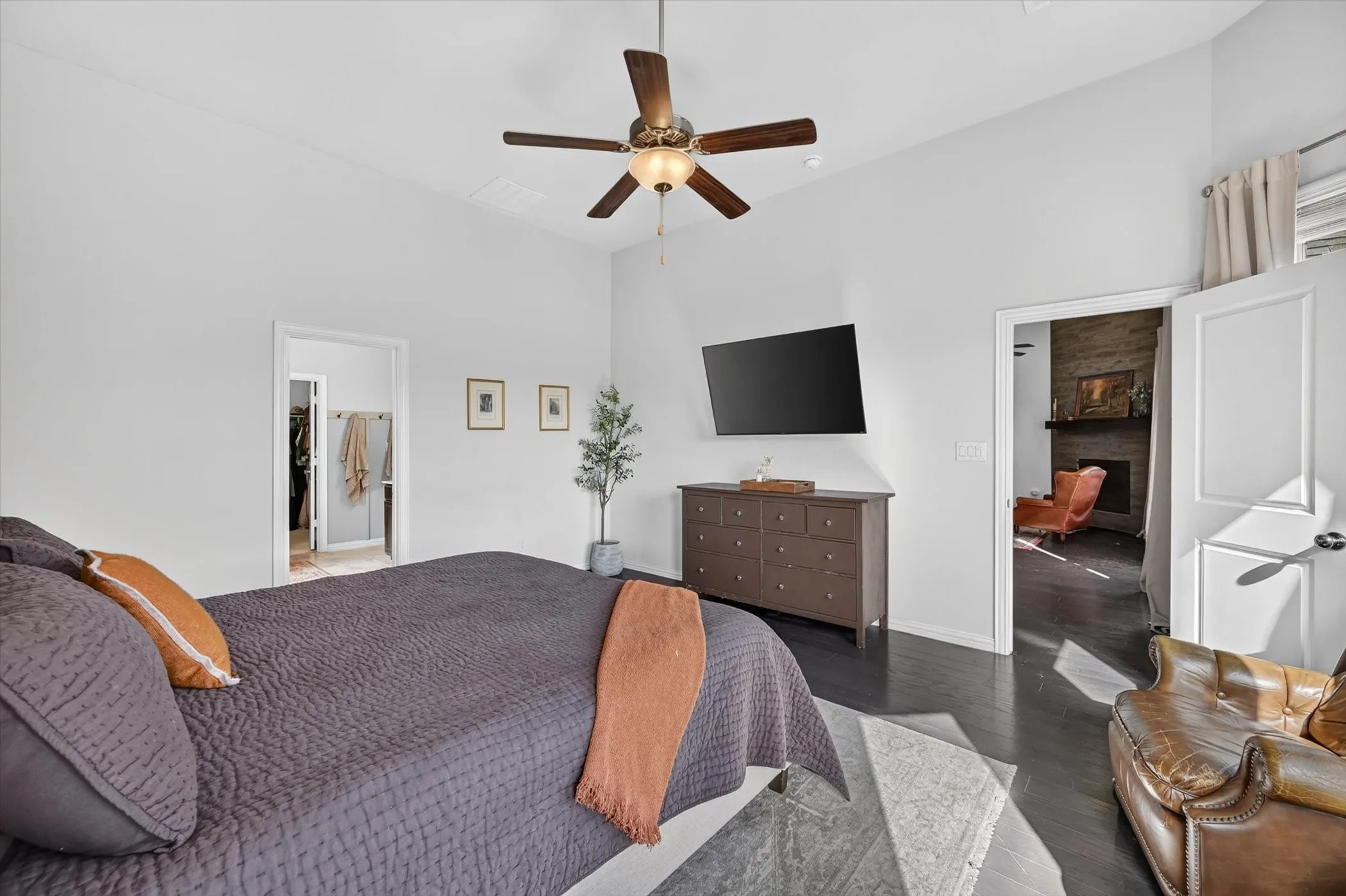 Spacious bedroom featuring vaulted ceilings, dark wood-finish flooring, a ceiling fan with integrated lighting, and white paneled doors