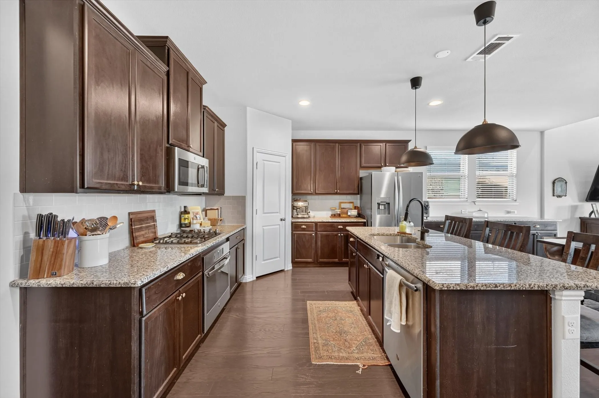 Expansive kitchen featuring wood-finish flooring, dark wood cabinetry, and light-toned countertops