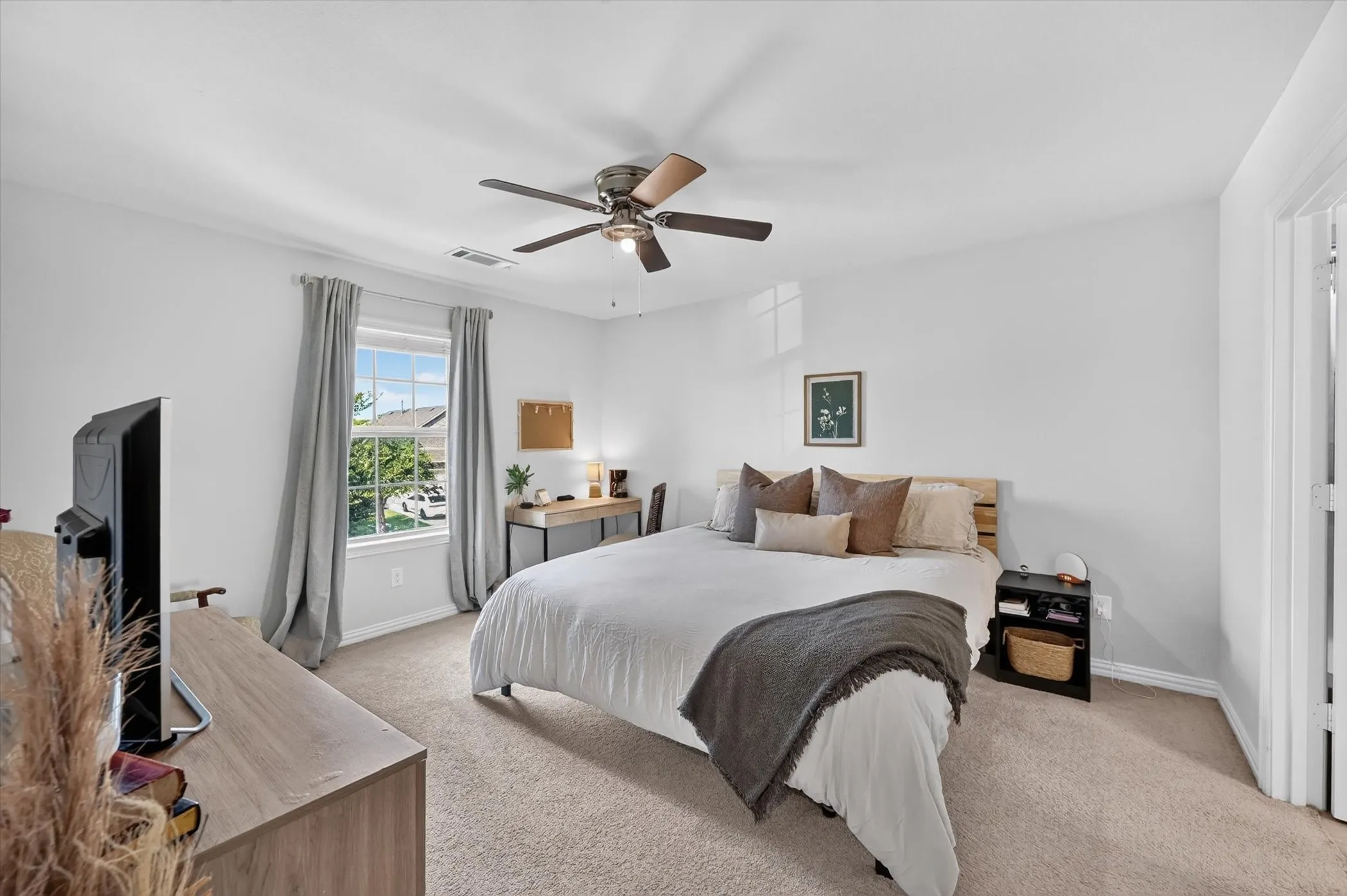 Spacious bedroom featuring light-colored walls, crown molding, a window with exterior views, and a ceiling fan with integrated lighting