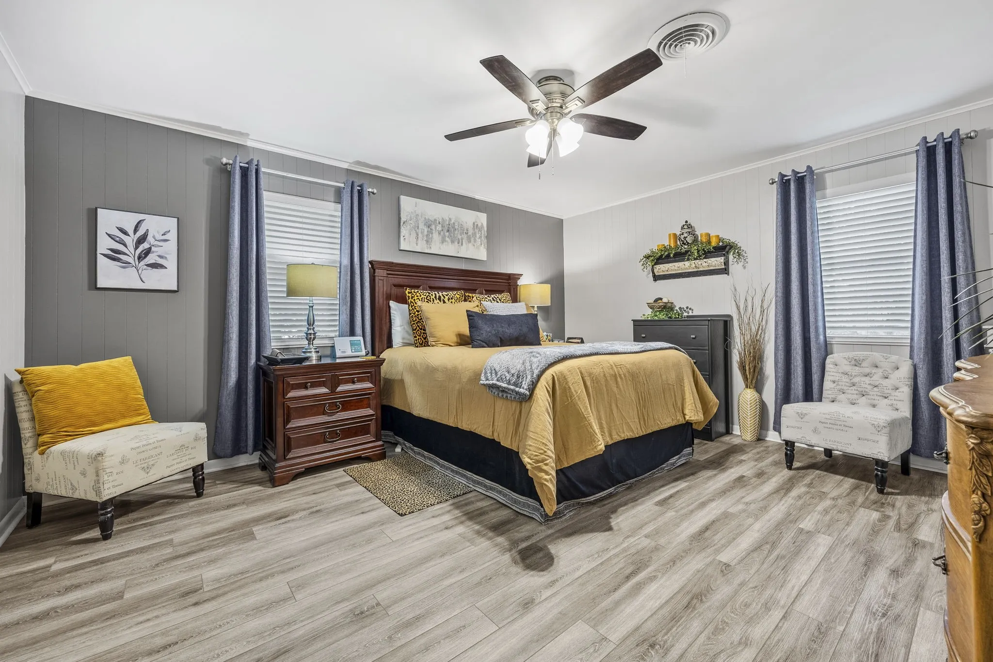 Primary Spacious room featuring wood-finish flooring, a ceiling fan with integrated lighting, and multiple windows with blinds