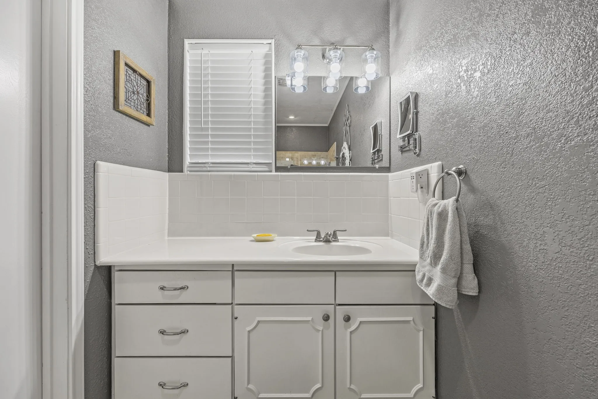 Bathroom vanity featuring a white countertop with an integrated sink, and a white cabinet with drawers and cabinet doors