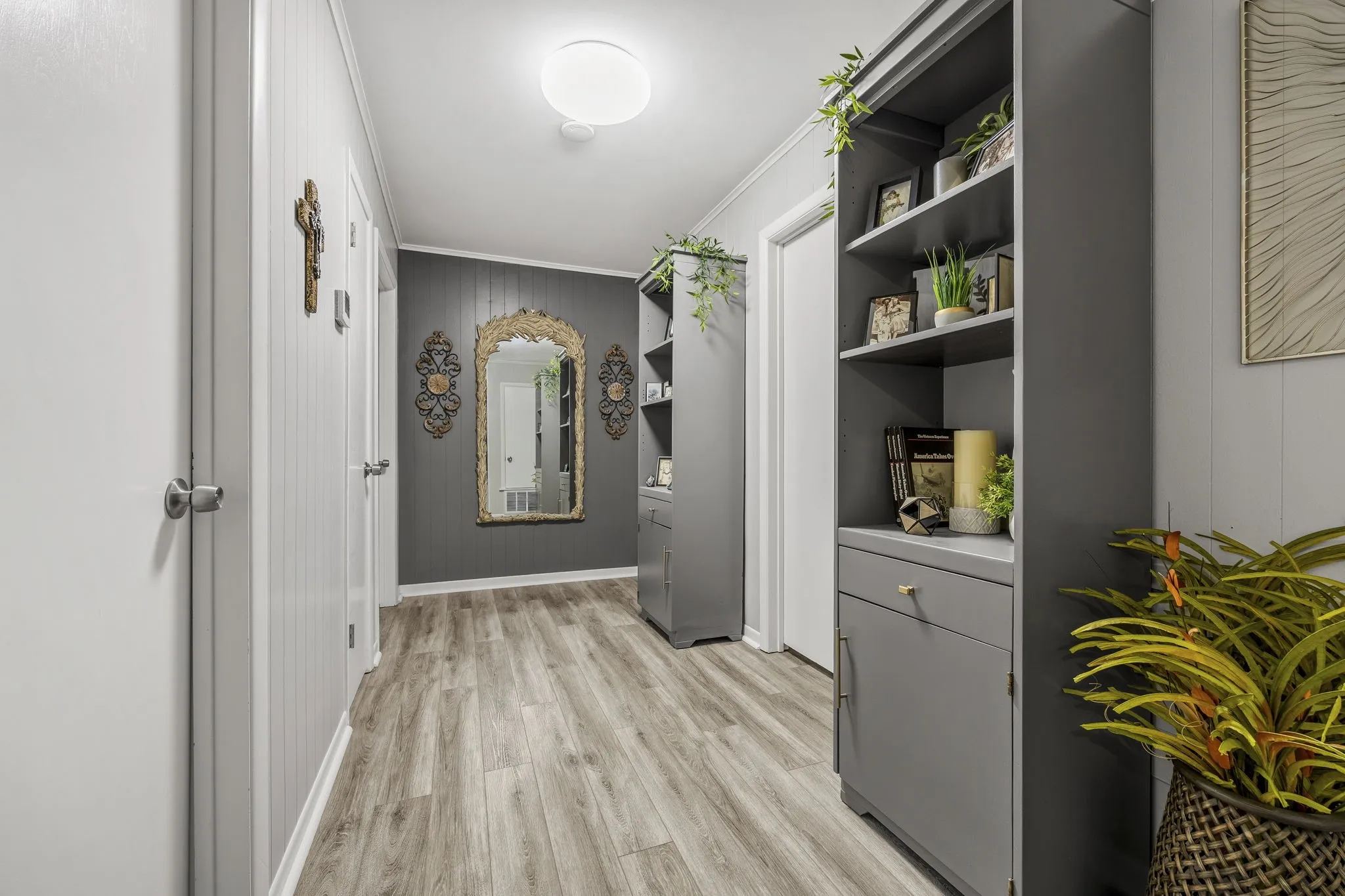 Hallway featuring wood-finish flooring, white paneled walls, and plent of space