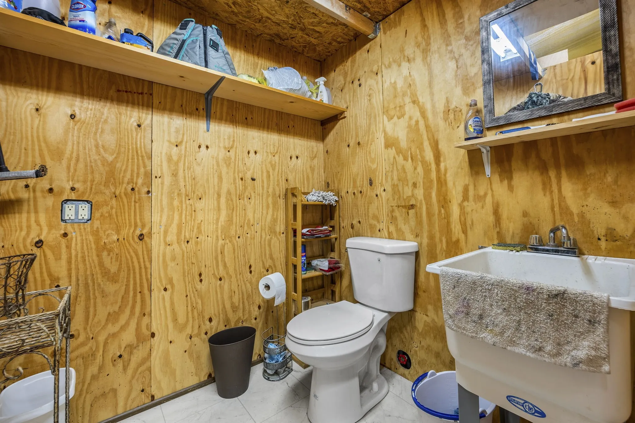 Workshop featuring a toilet, and a utility sink and plenty of storage
