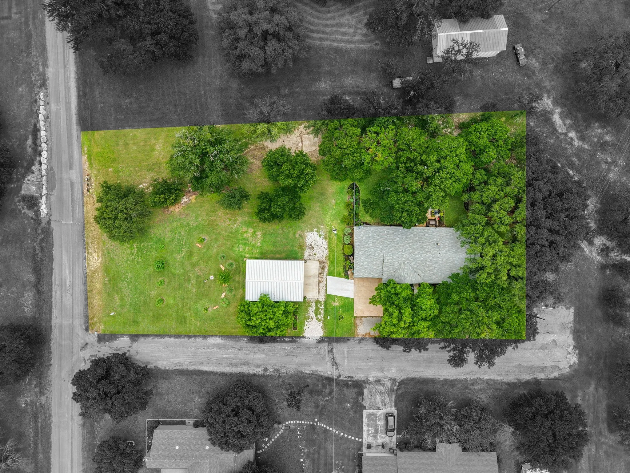 Expansive property featuring a main residence with  mature trees, a detached outbuilding with and a paved driveway