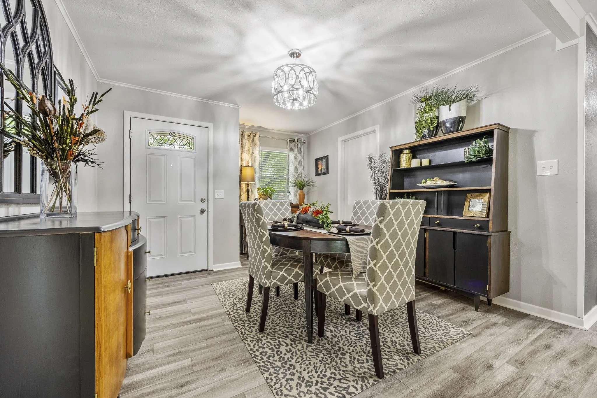 Dining area featuring wood-finish flooring, crown molding, and a decorative chandelier