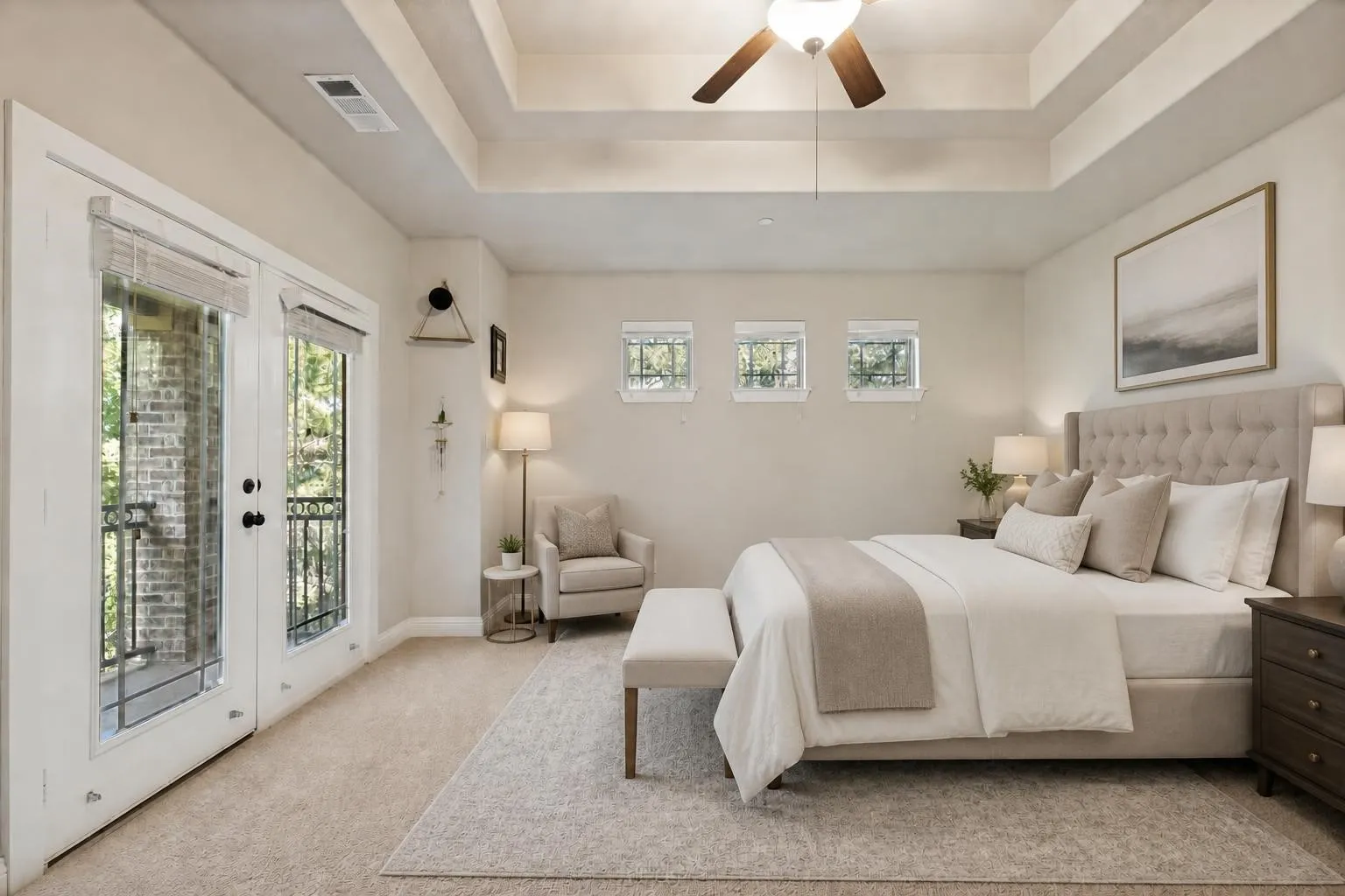 Virtually staged primary bedroom with trayed ceilings and balcony