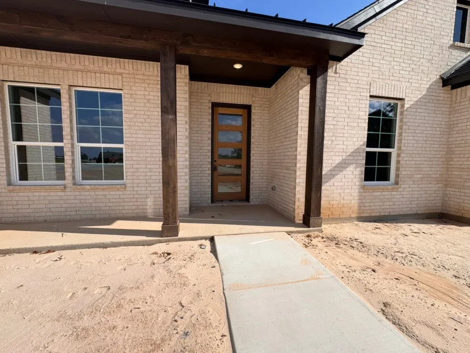 Light-toned brick exterior with dark wood-finish columns and front door