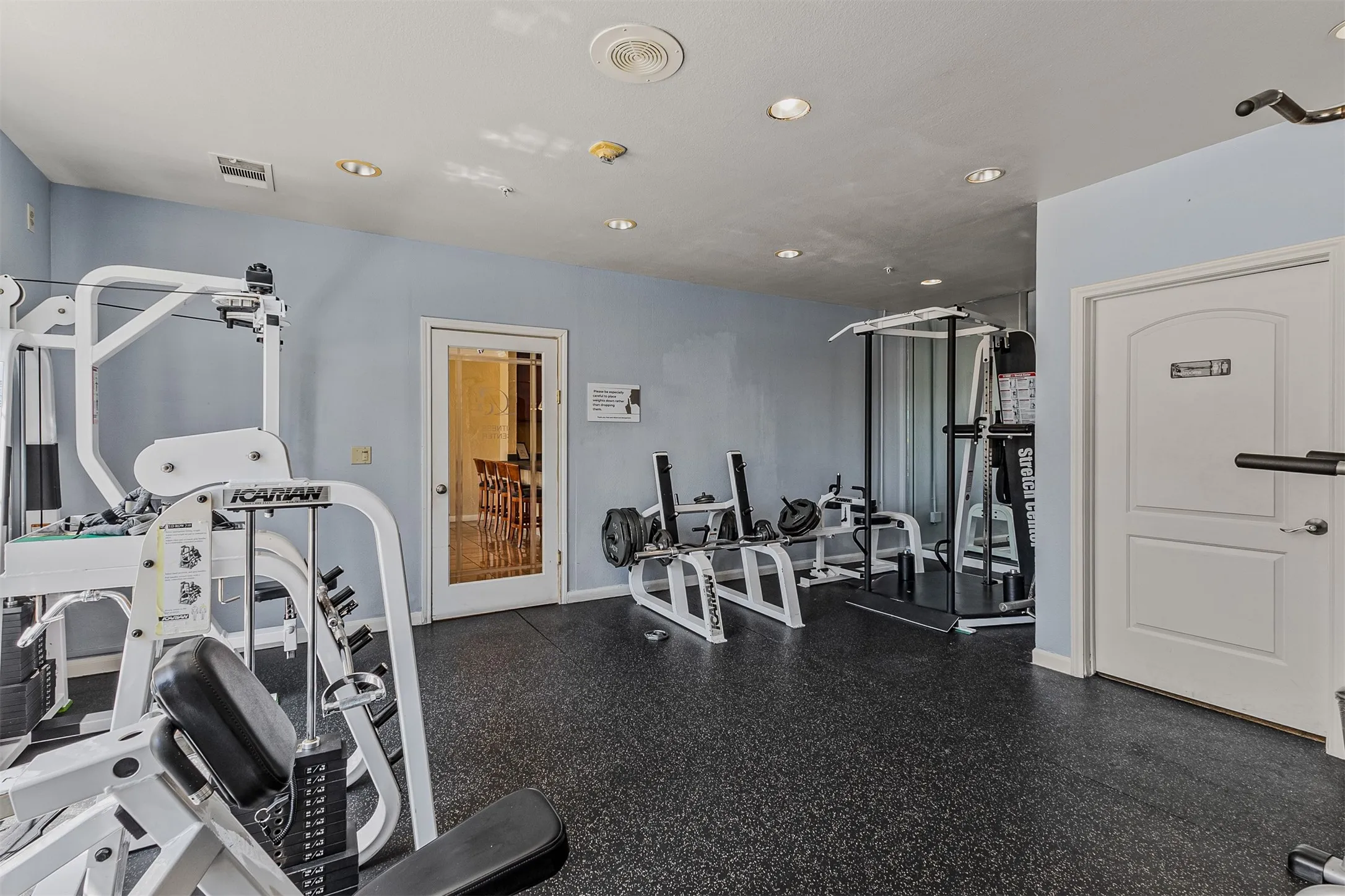 Dedicated fitness room with specialized rubber flooring and recessed lighting