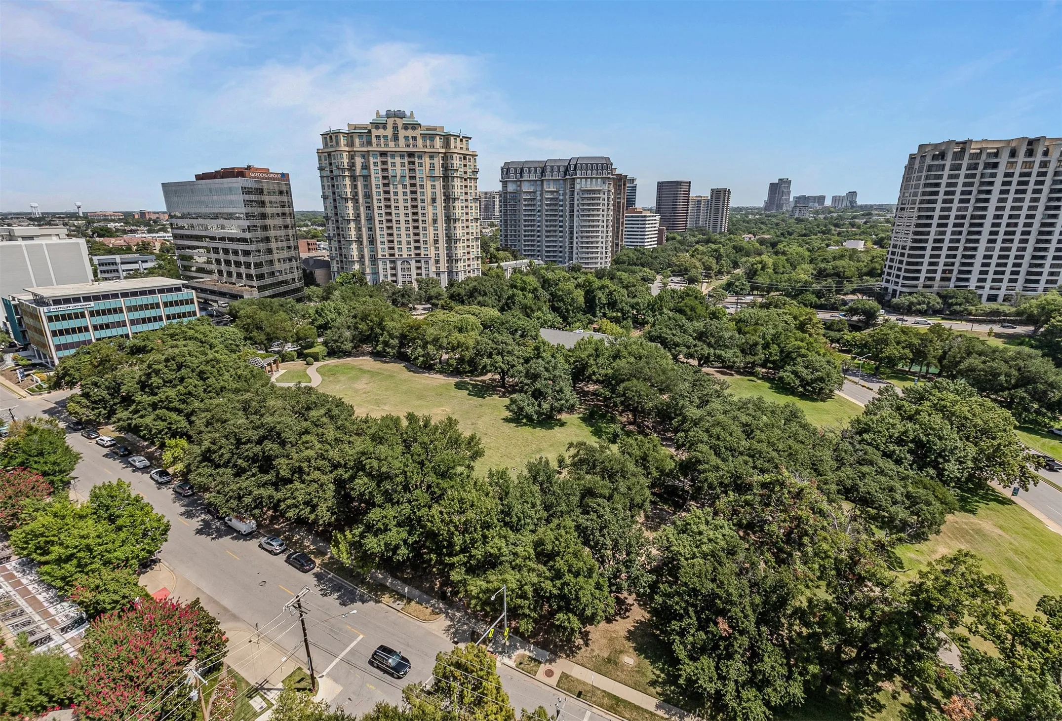 Urban parkland featuring mature trees and a central green space