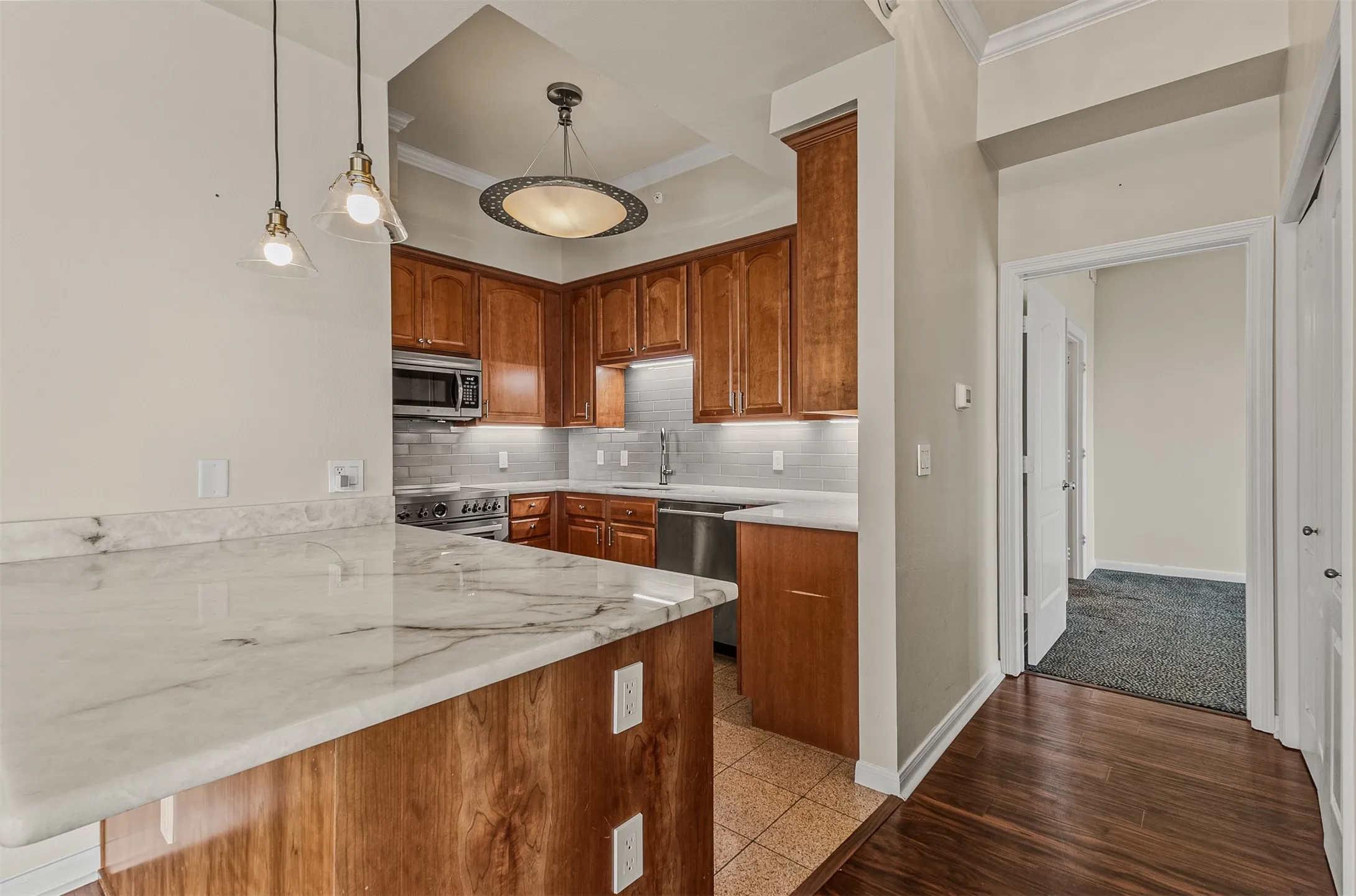 Kitchen featuring wood cabinetry, stainless steel appliances, a white subway tile backsplash, and a large breakfast bar with a light-toned countertop
