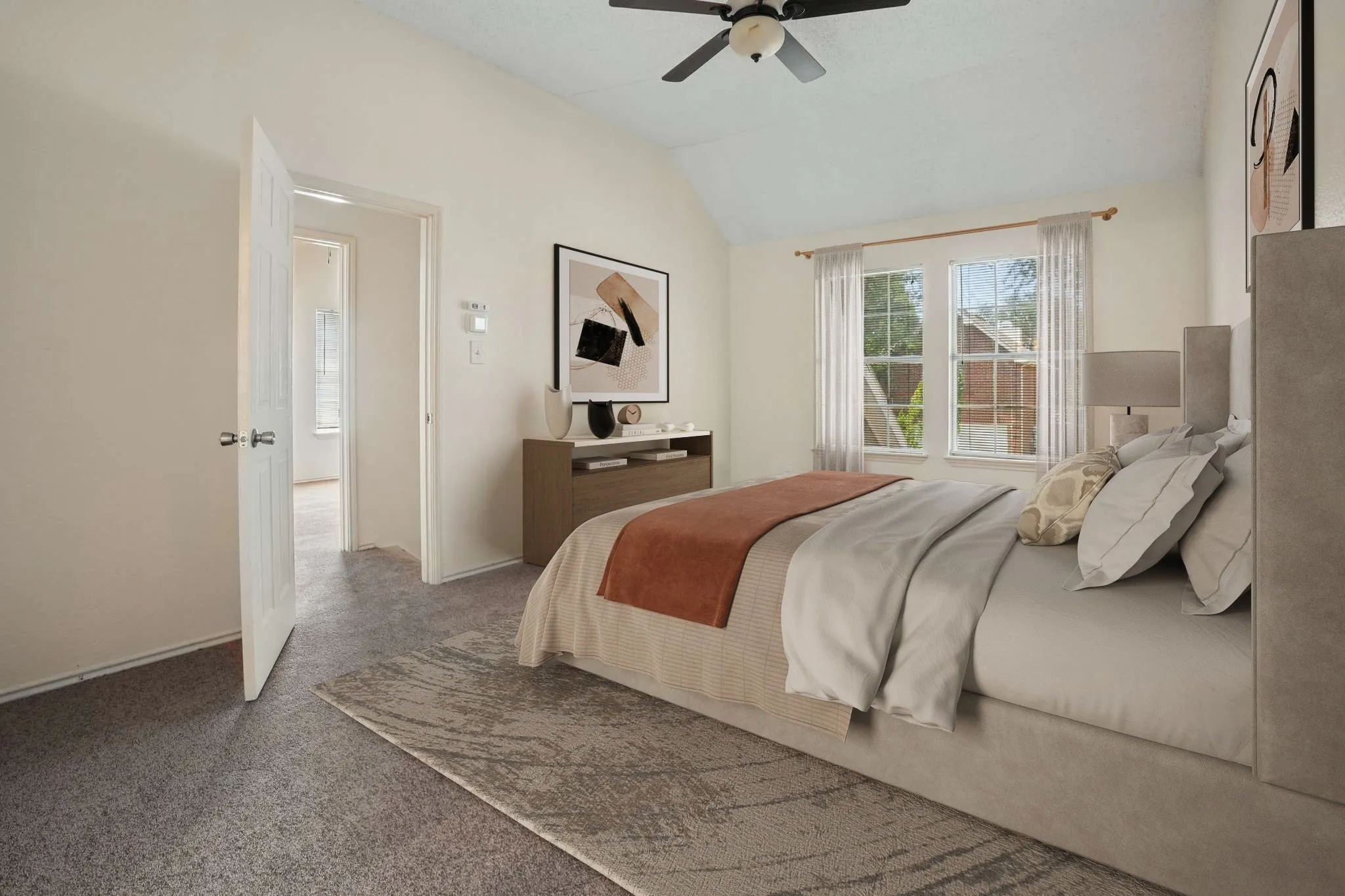 Carpeted bedroom featuring vaulted ceilings, a ceiling fan, two windows with curtains, and a solid core door