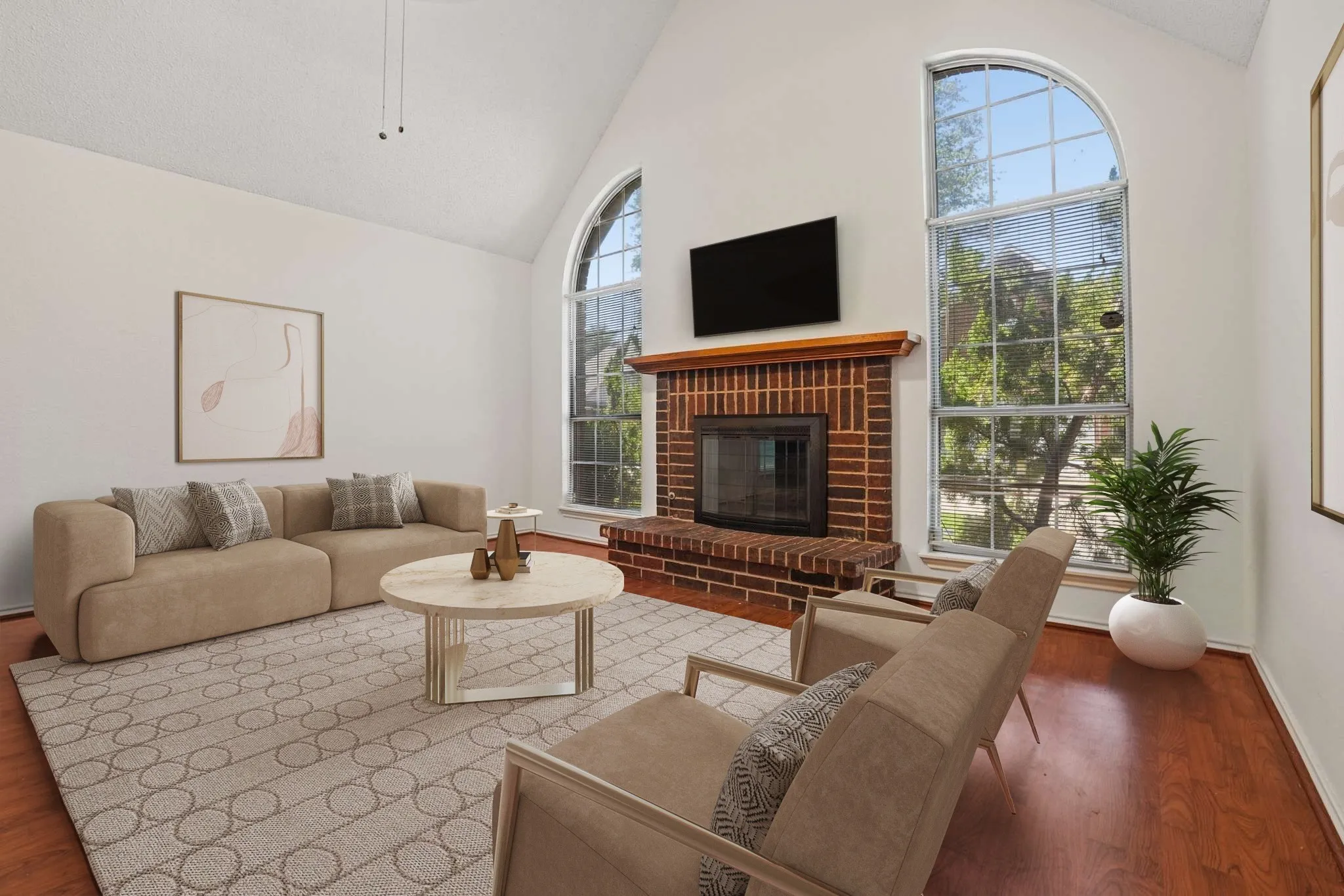 Vaulted ceiling living area featuring brick fireplace, wood-finish flooring, and two arched windows