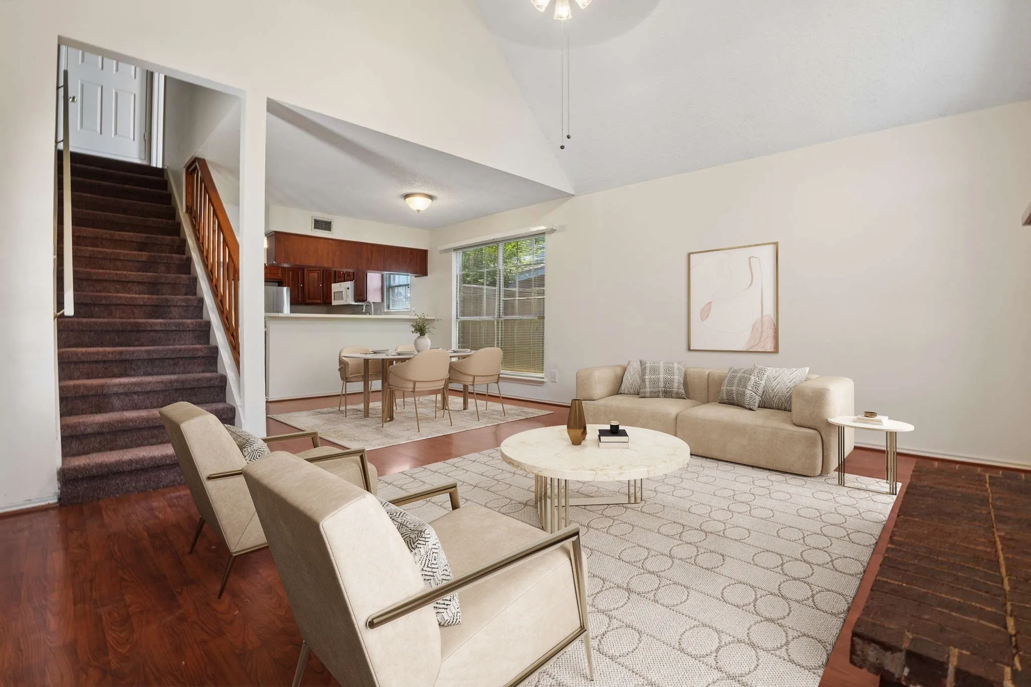 Spacious living area featuring vaulted ceilings, wood-finish flooring, and a brick fireplace