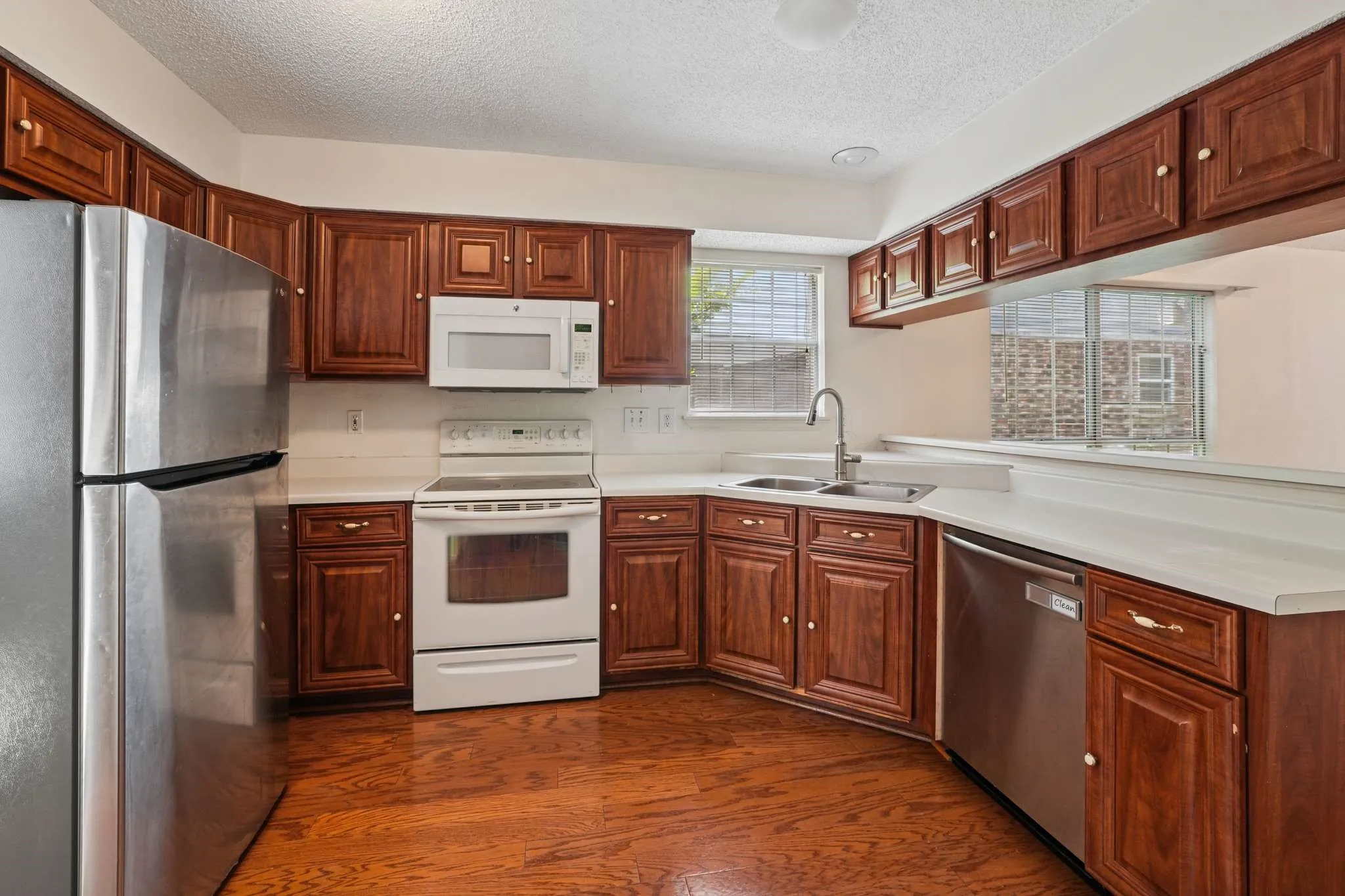 Kitchen featuring wood-finish flooring, dark wood cabinetry, white countertops, and a stainless steel refrigerator
