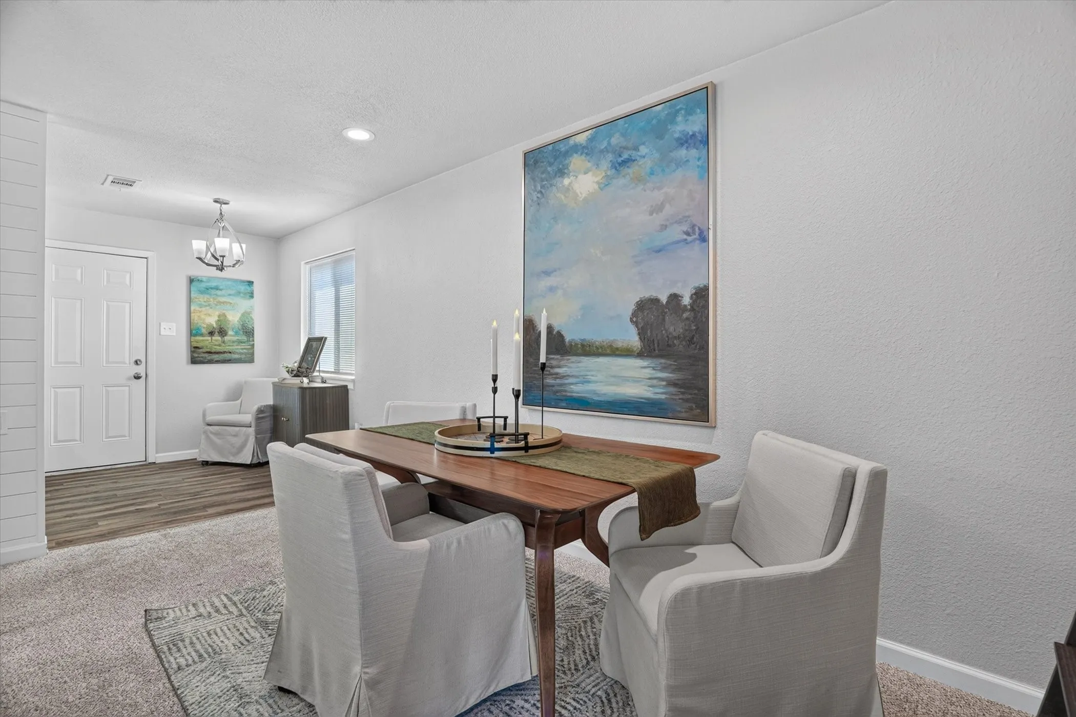 Carpeted flooring with an area rug complements smooth painted walls and a window with natural light