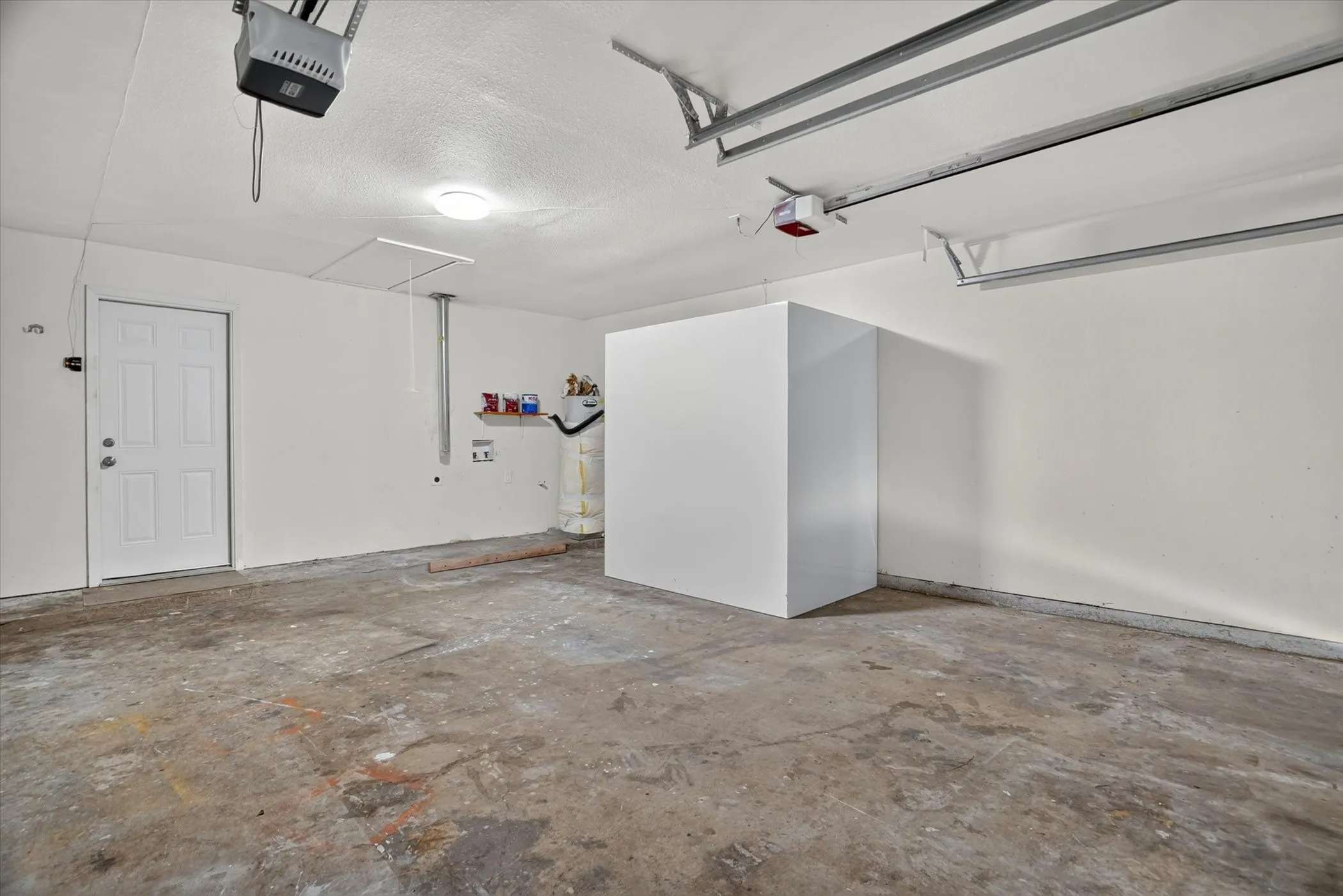 Attached two-car garage featuring a panel door, overhead lighting, and concrete flooring