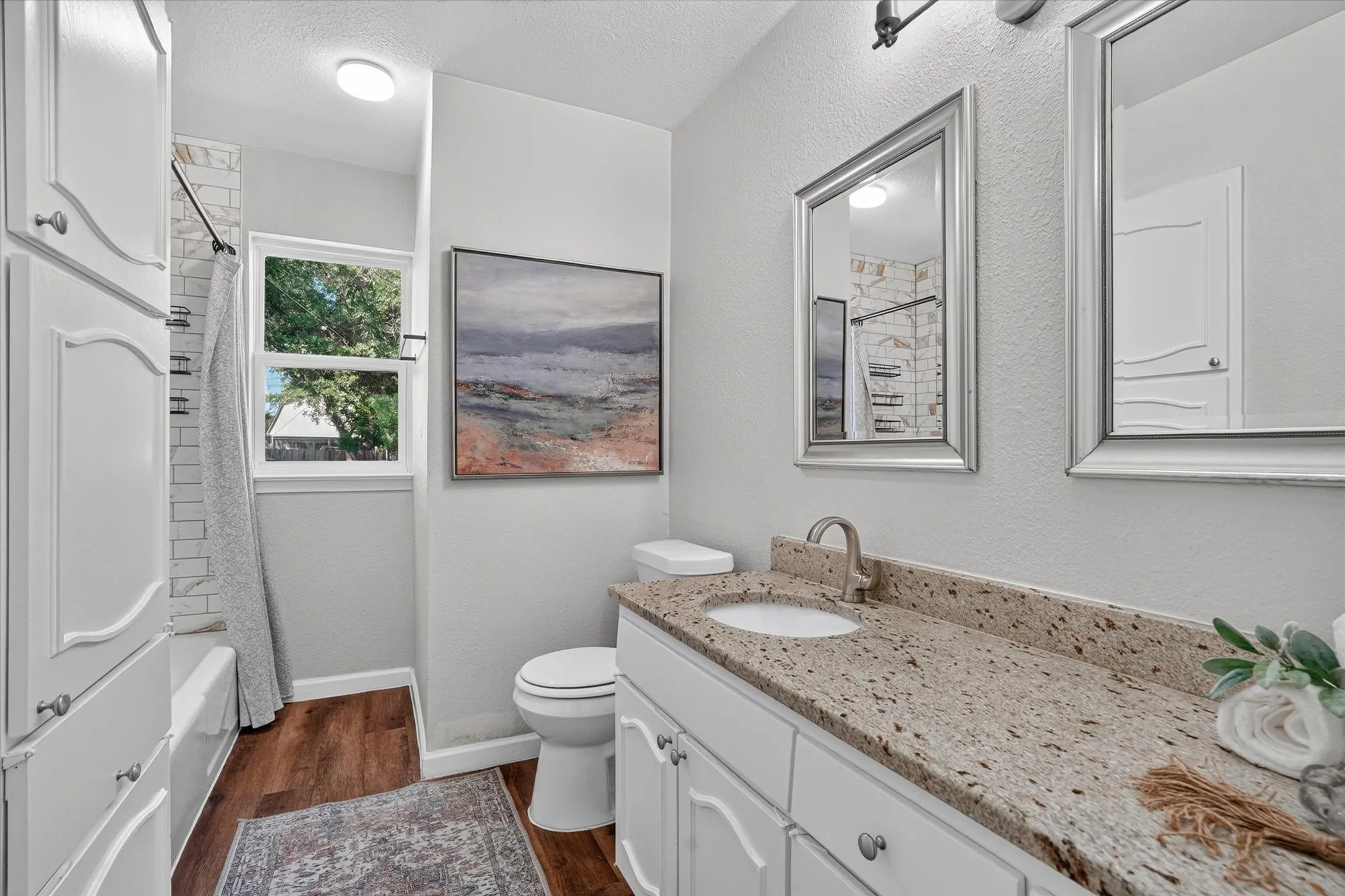 Bathroom featuring a dual vanity with a speckled countertop, a white under-mount sink, and dual framed mirrors