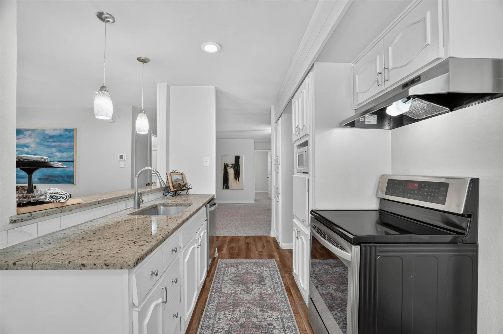 Kitchen featuring white cabinetry, granite countertops, stainless steel sink, wood-finish flooring, and recessed lighting