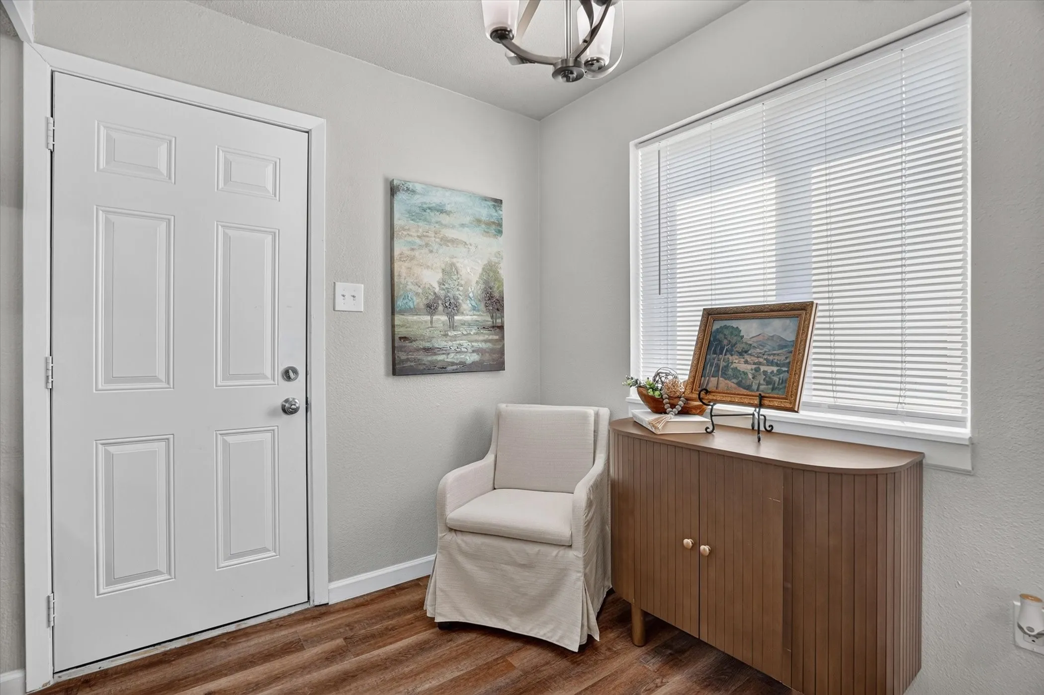 Entryway featuring a paneled white door, wood-finish flooring, and a window with blinds