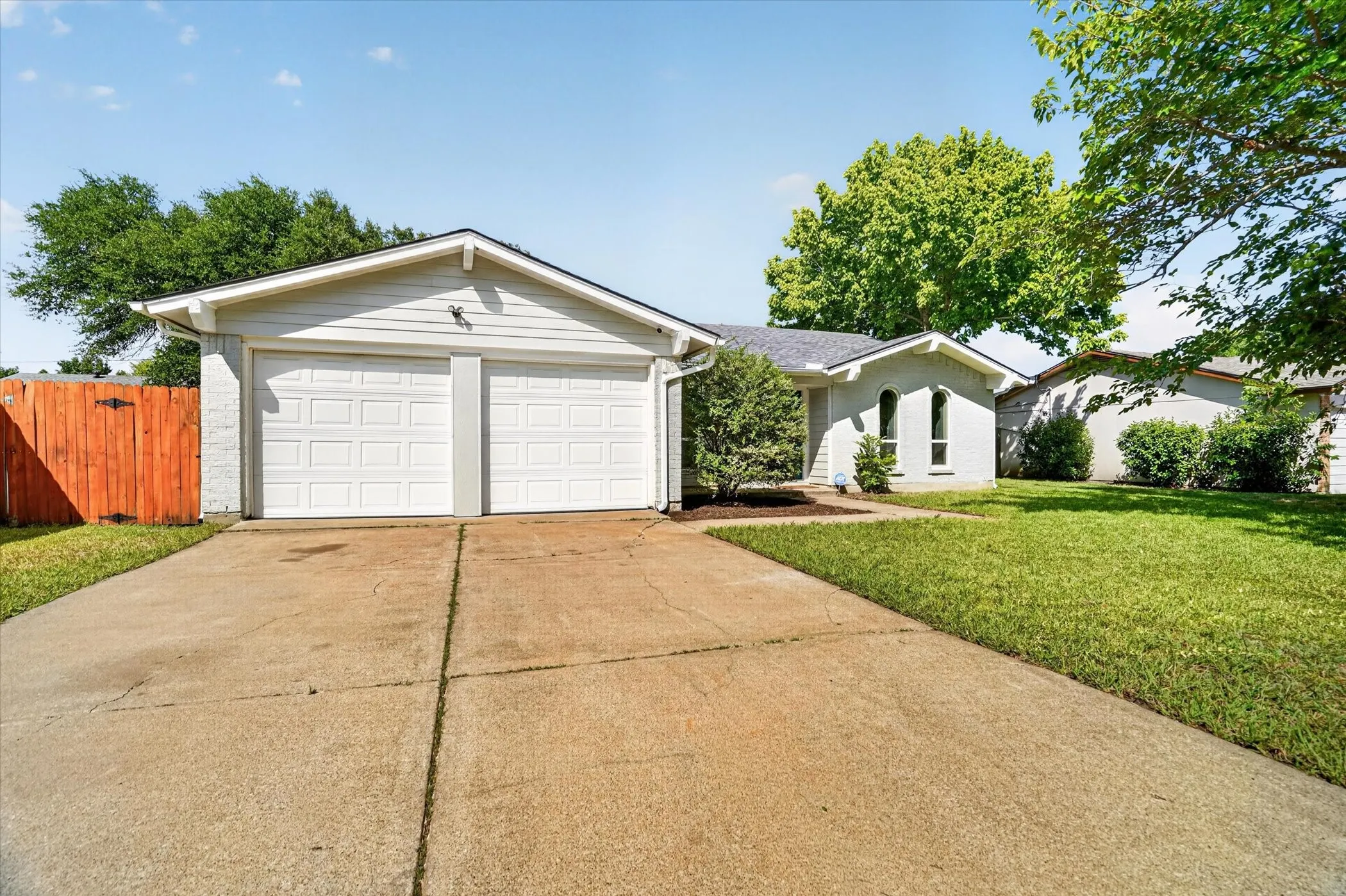 Single-story residence featuring a two-car garage with panel doors, a concrete driveway, and a manicured lawn