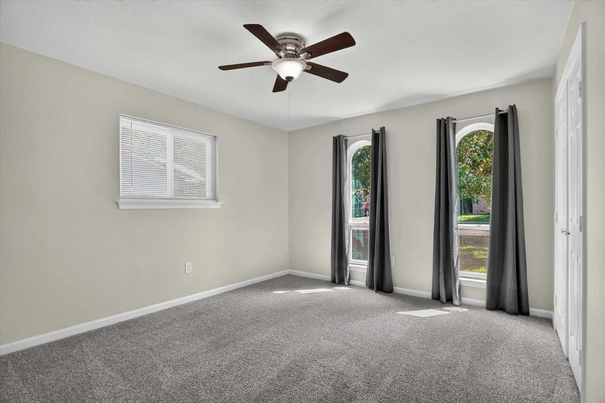 Spacious room featuring neutral painted walls and gray carpeting
