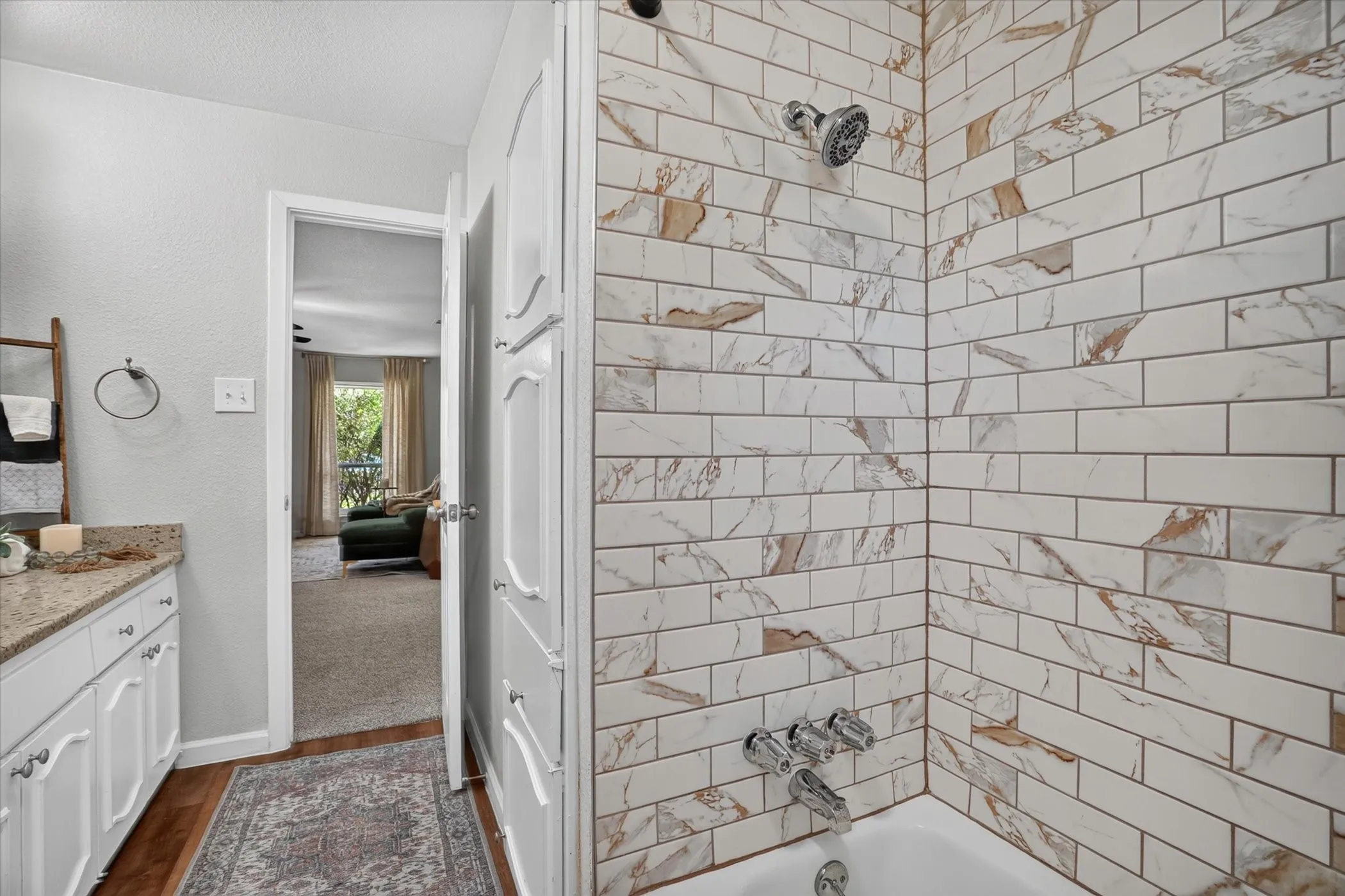 Bathroom featuring subway tile shower surround with integrated bathtub, chrome fixtures, and built-in white cabinetry