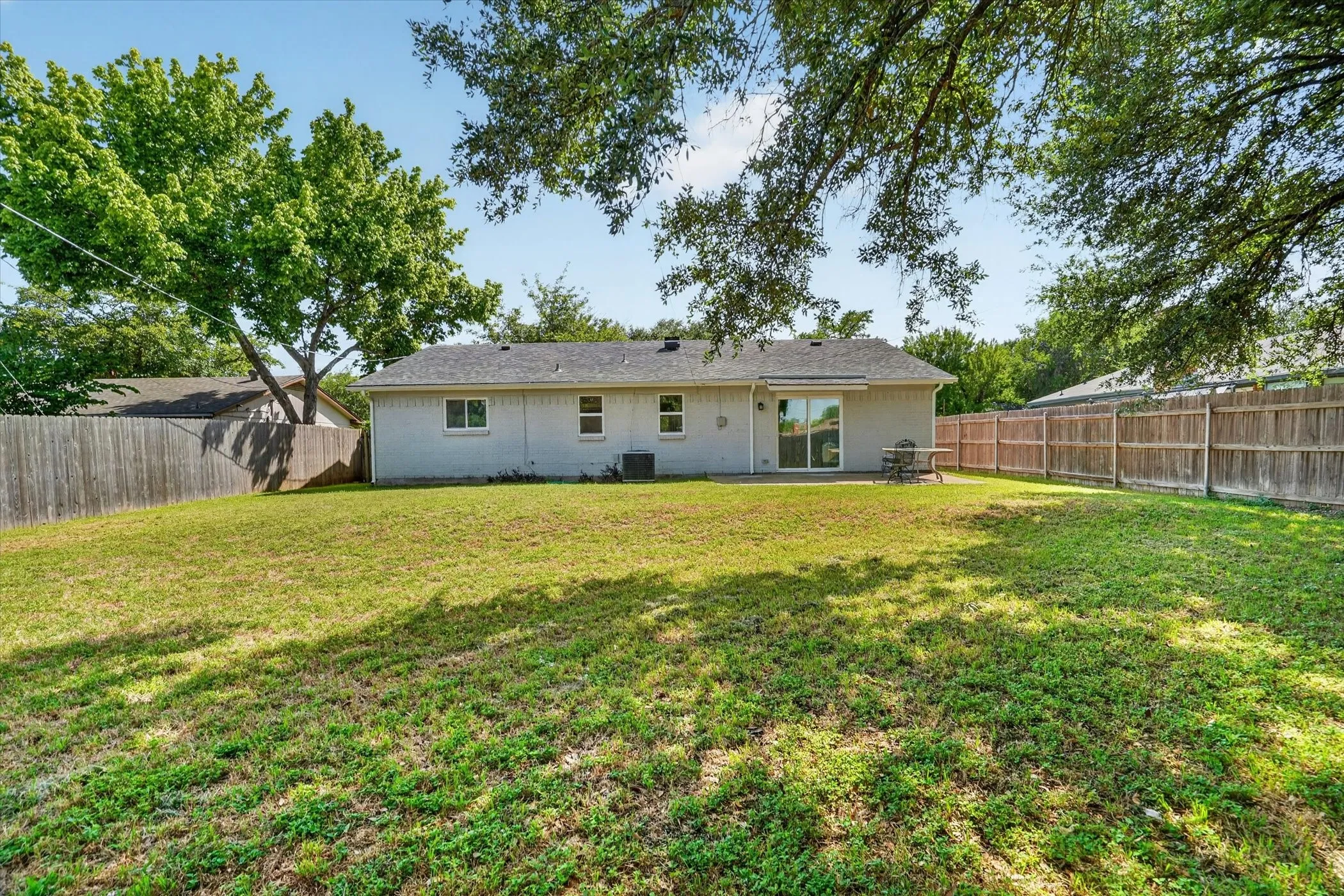 Expansive backyard featuring a lush lawn and perimeter wood fencing