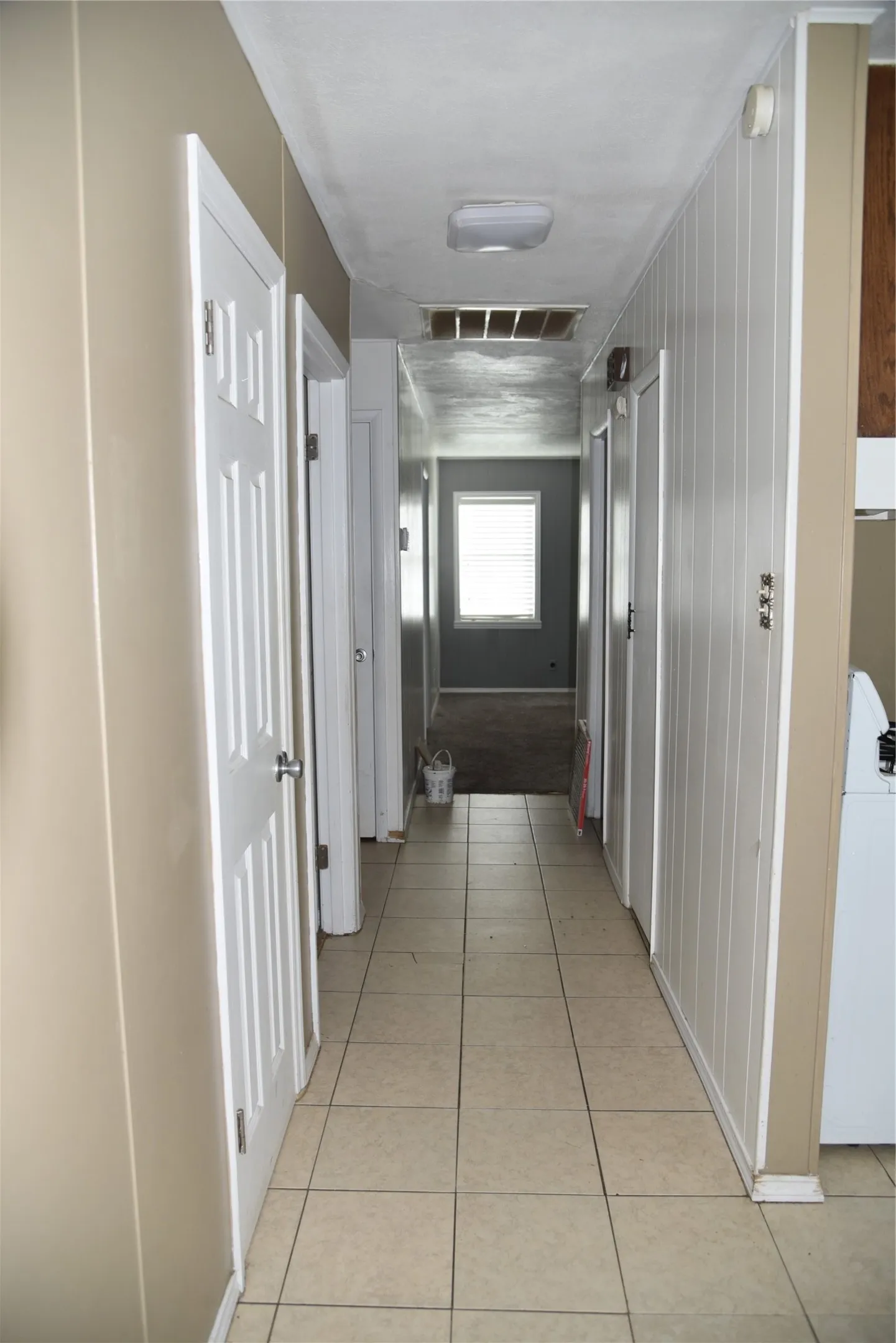 Hallway featuring ceramic tile flooring, neutral wall tones, and white paneled doors