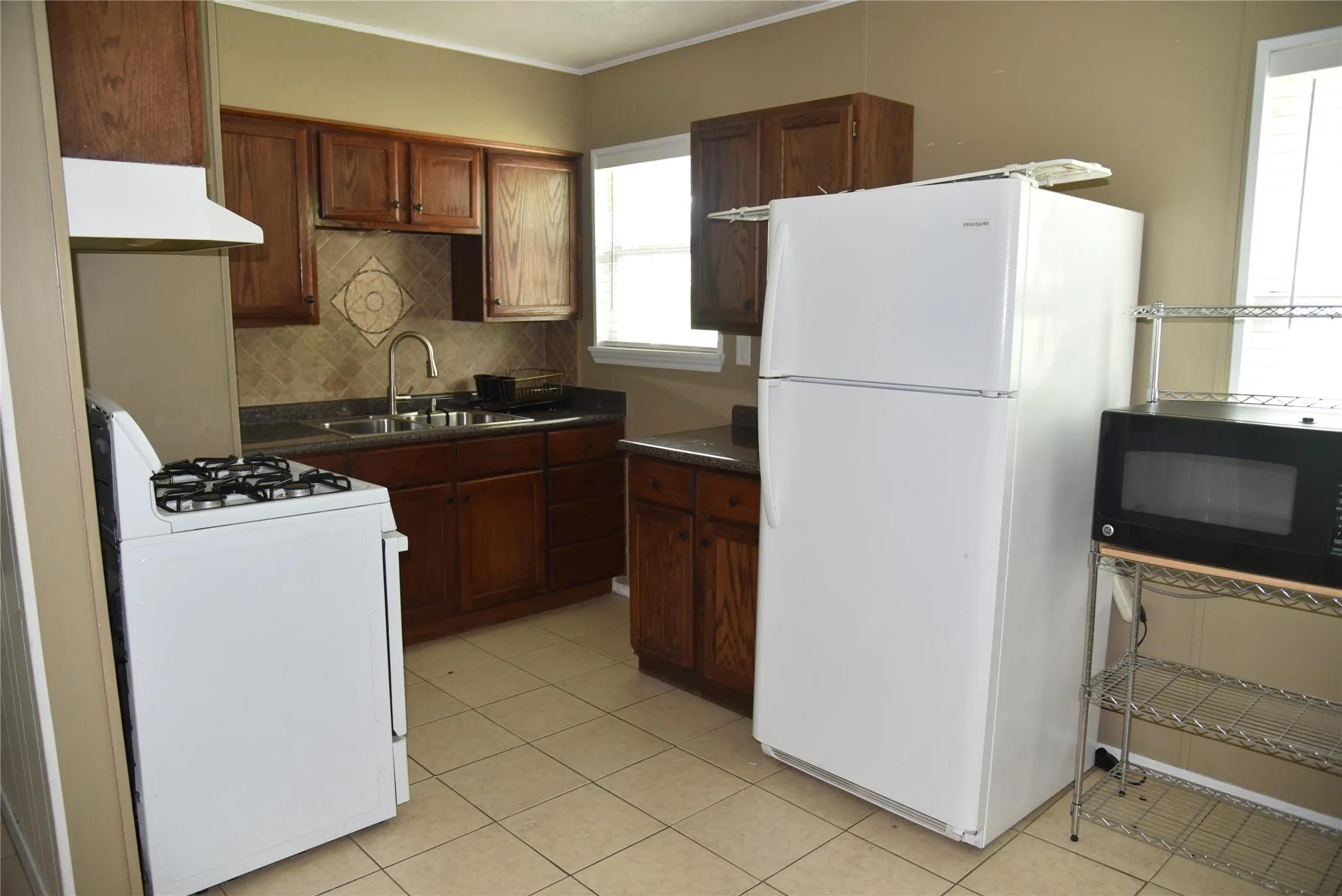 Kitchen featuring wood cabinetry, tiled backsplash, and dark countertops