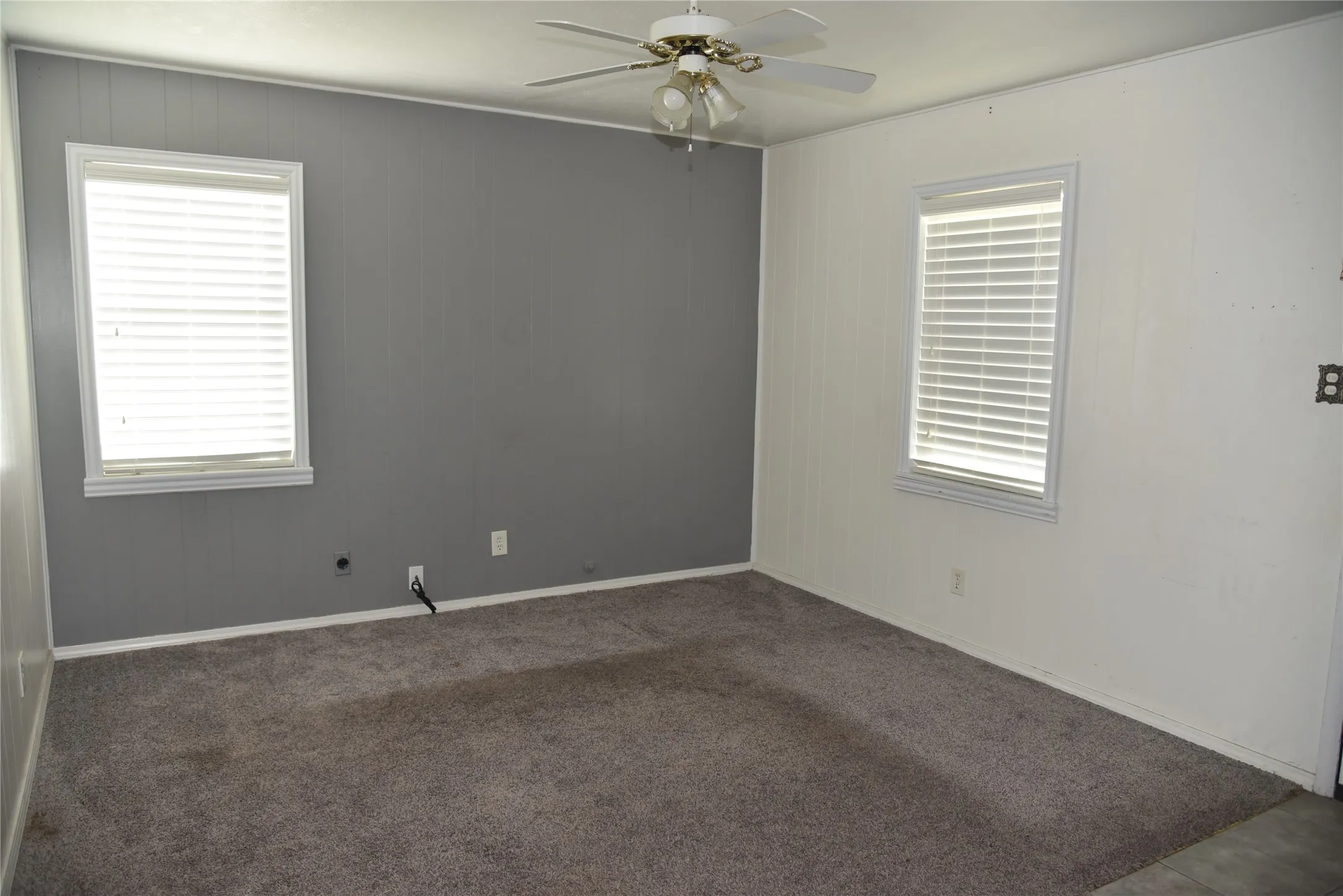 Room featuring neutral gray carpeting and white paneling on three walls