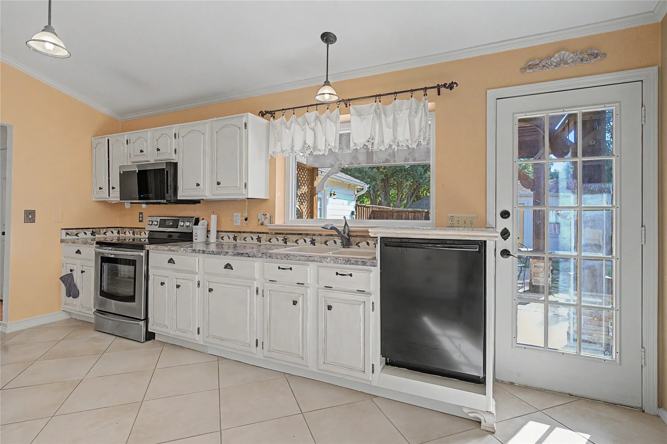 Kitchen featuring white cabinetry, stainless steel range and microwave, black dishwasher, and tiled flooring