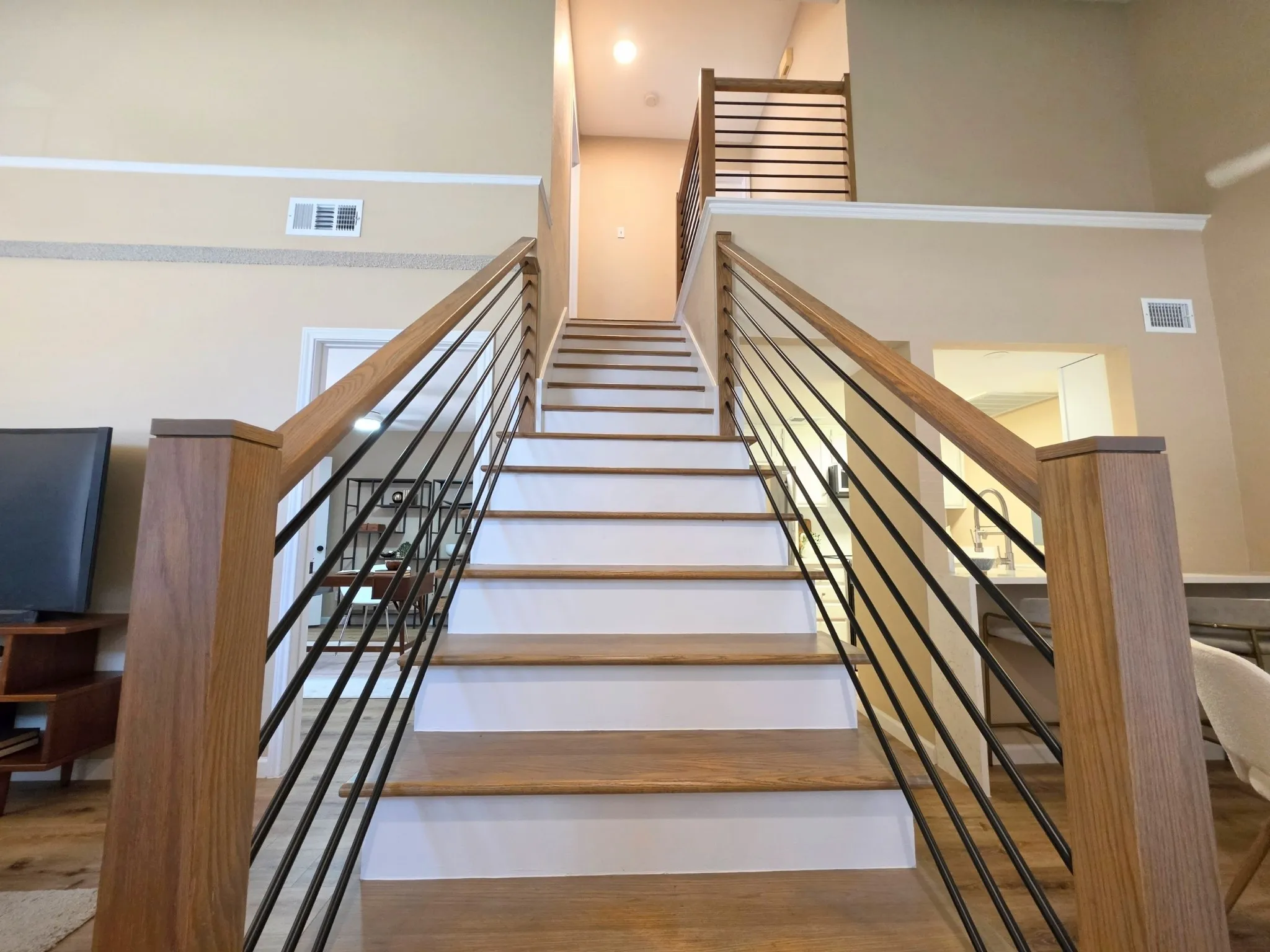 Staircase featuring wood with white risers, and a contemporary railing with wooden posts and black metal balusters