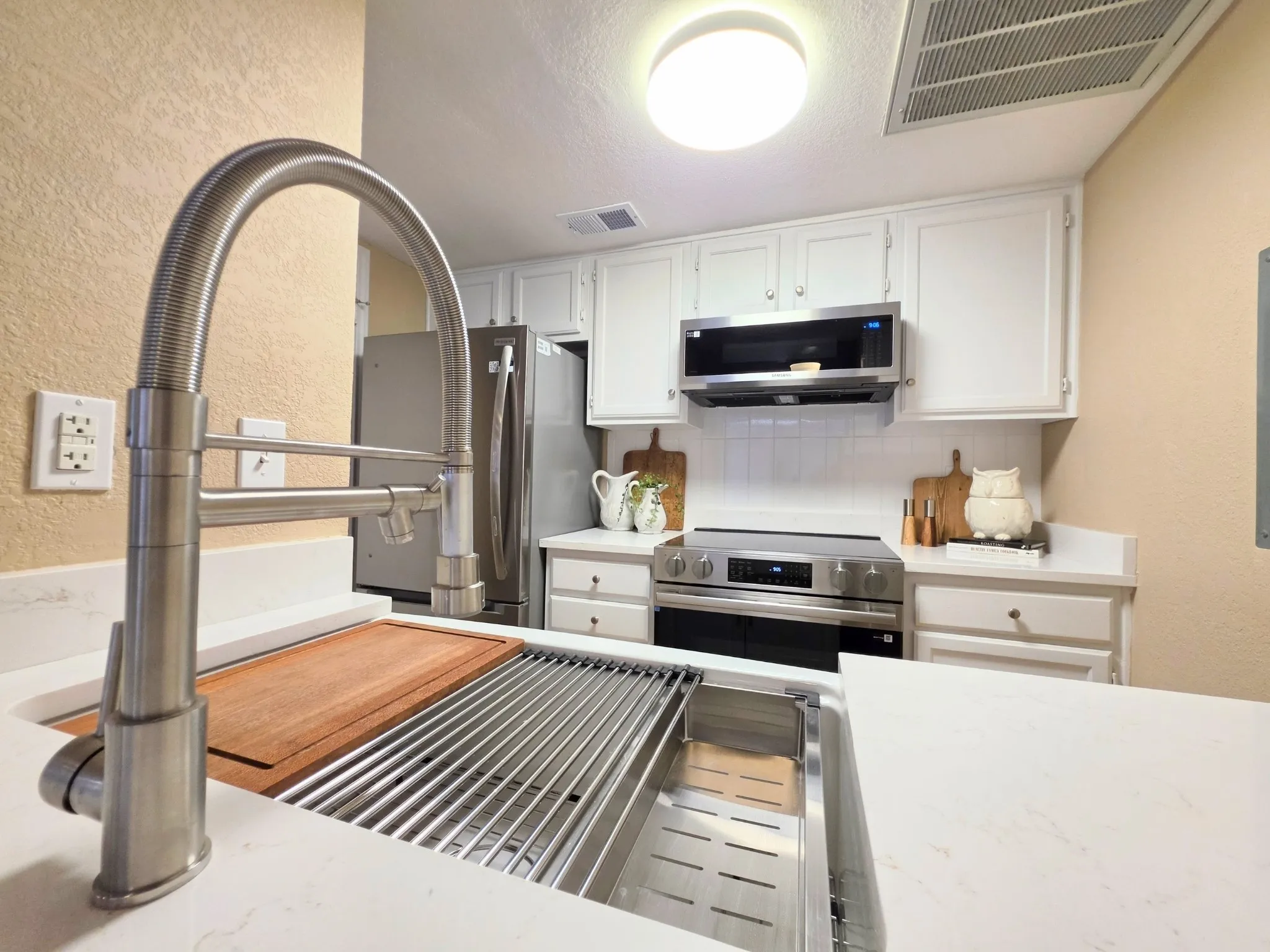 Kitchen featuring white shaker cabinetry, stainless steel appliances, a subway tile backsplash, white countertops, and a modern brushed nickel faucet with a deep farmhouse sink
