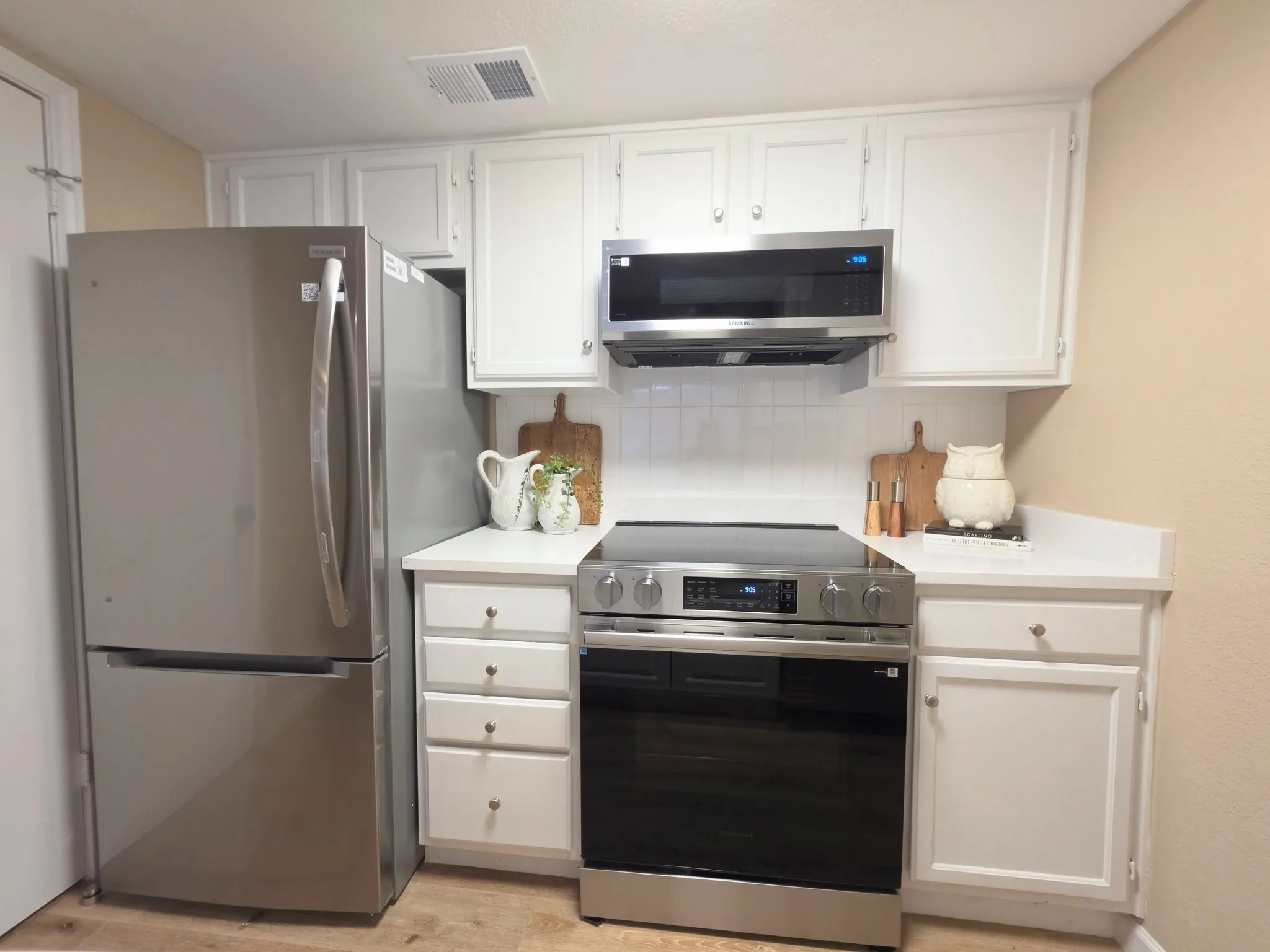 Kitchen featuring stainless steel appliances, white cabinetry, solid surface countertops, and a subway tile backsplash
