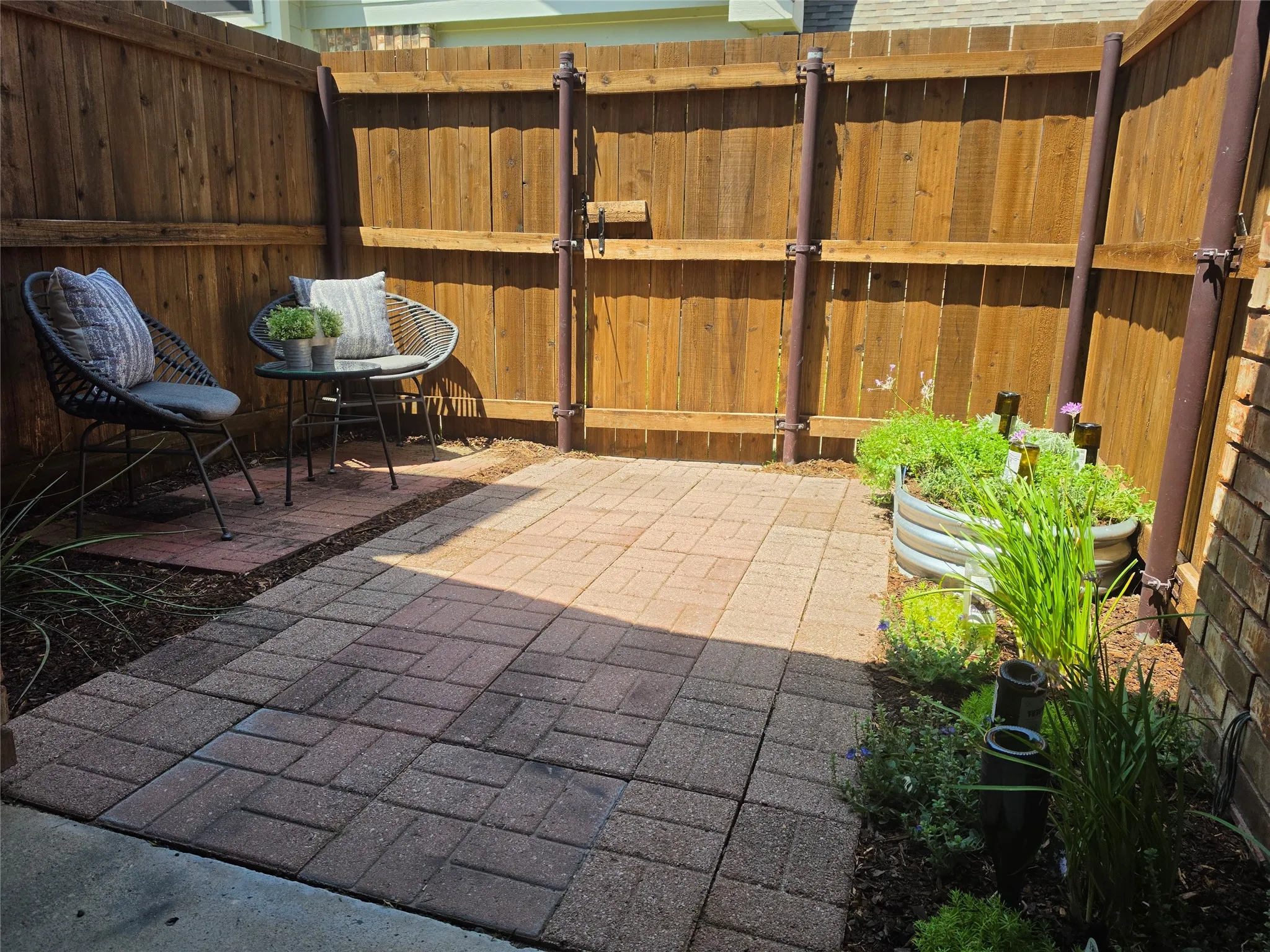 Private outdoor patio featuring paver stone flooring, natural wood fencing, and perimeter landscaping