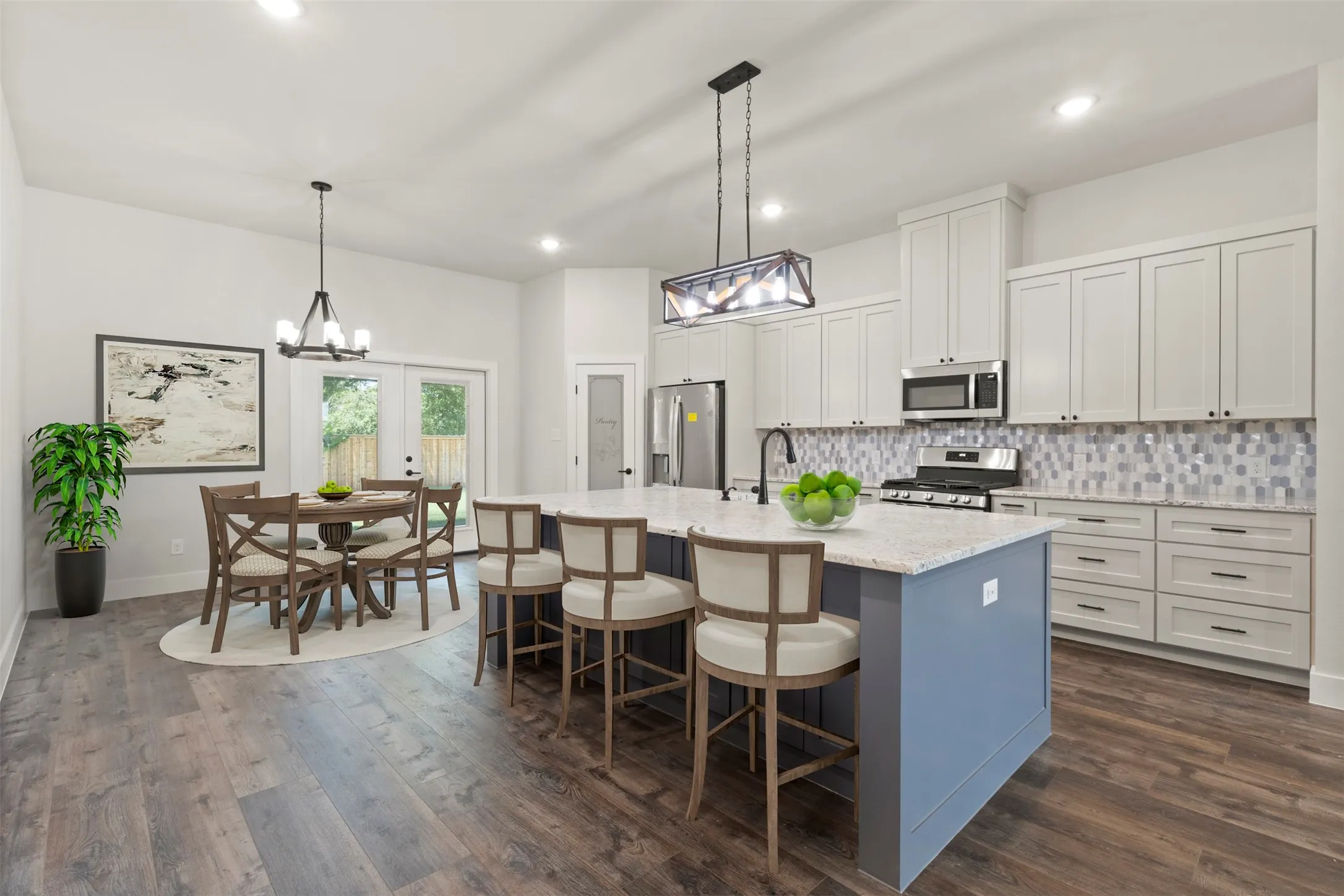 Open-concept kitchen featuring an oversized island with seating, a mosaic tile backsplash, stainless steel appliances, and abundant white cabinetry