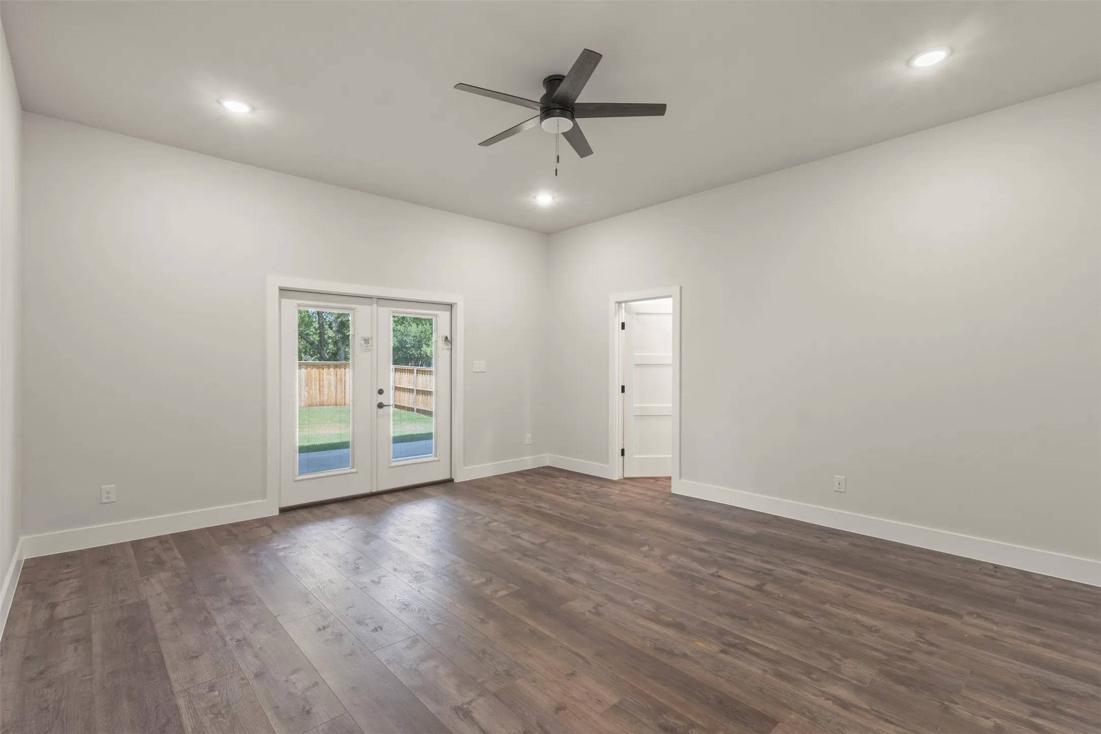 Spacious room featuring wood-finish flooring, recessed lighting, and a ceiling fan