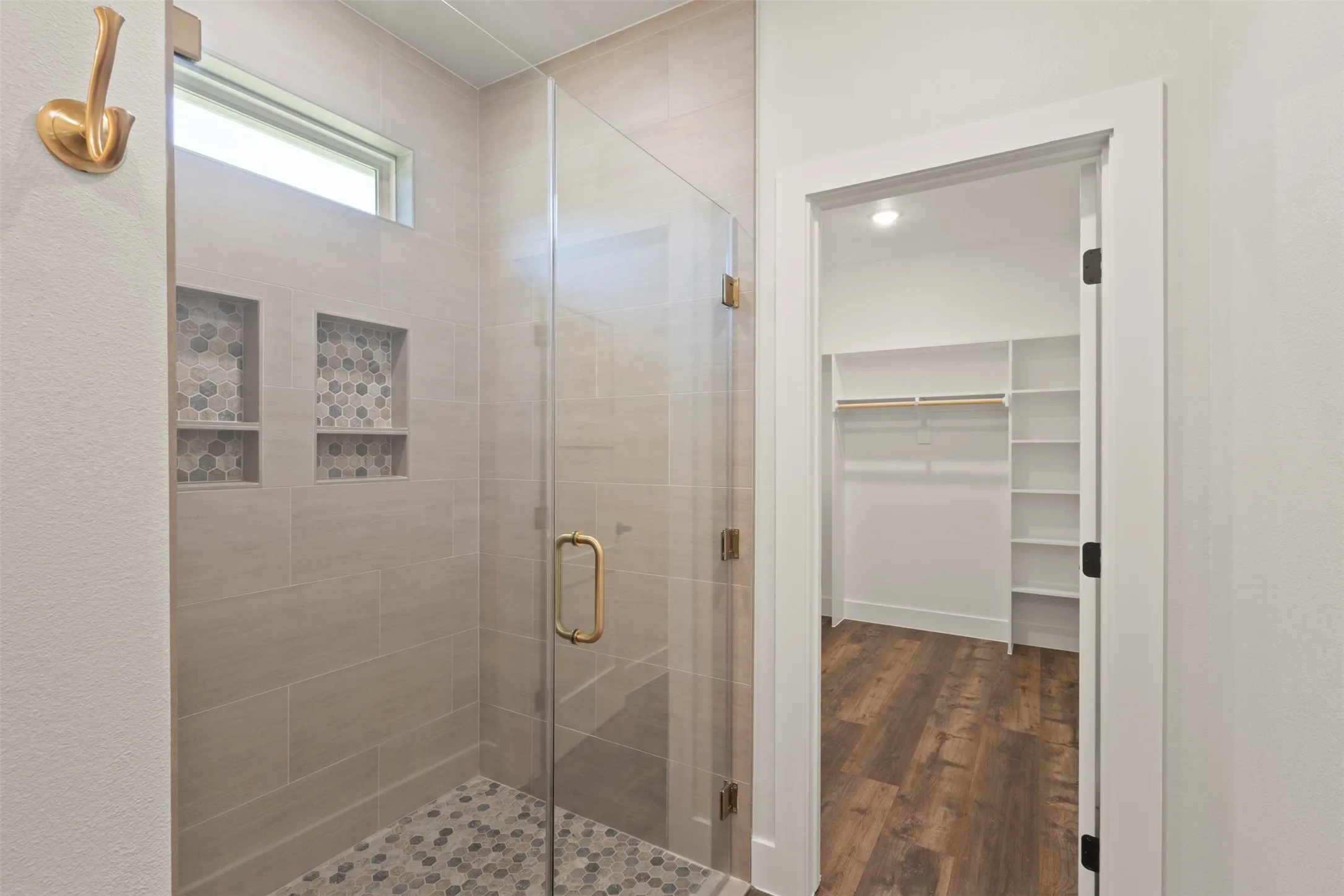 Spacious shower with glass enclosure, light-toned tile walls, and mosaic-tiled shower floor