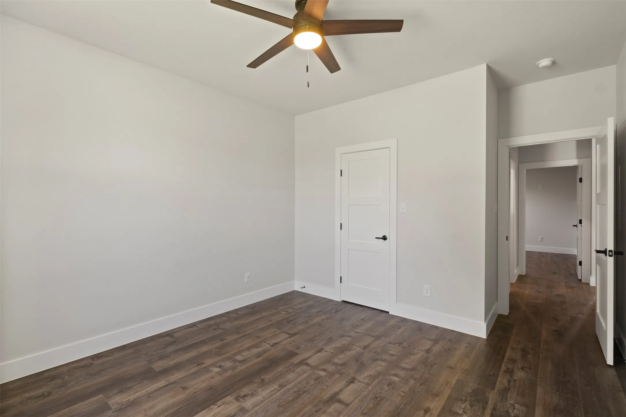 Spacious room featuring wood-finish flooring, light grey walls, and white trim